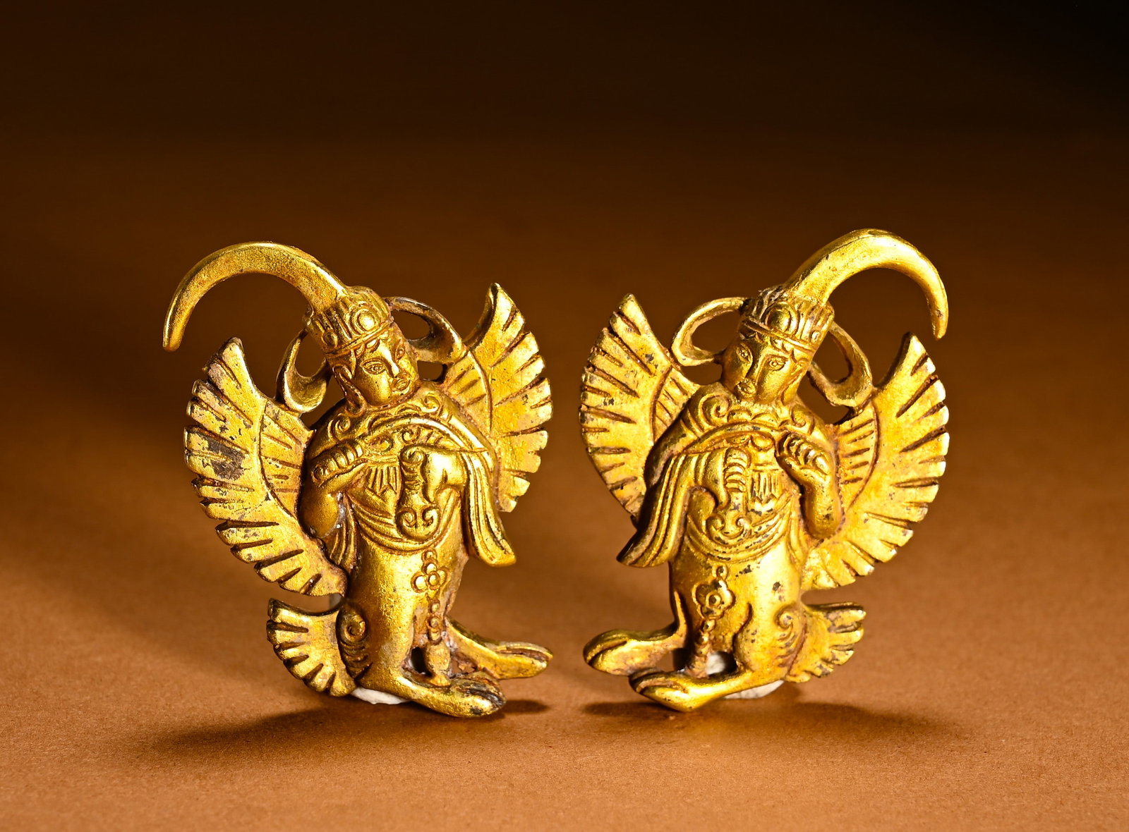 LIAO DYNASTY, A PAIR OF GILT-BRONZE GARINGA PENDANTS: Gilt bronze pair of kinnara pendants. Buddhist mythical winged human-headed bird, symbolizing auspicious sound. Combining western Buddhist and nomadic craft, wearable ritual ornament.Dimensions: Width
