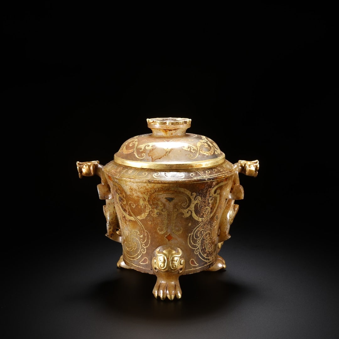 HAN HETIAN JADE INLAID WITH GOLD DOUBLE CHILONG DRAGON THREE-LEGGED COVERED VESSEL: Ancient lidded jade zun vessel with gold inlay, beast ears and three feet. Crafted from aged Hetian jade with mottled natural patina. The body is decorated with elaborate gold-inlaid scroll patterns a