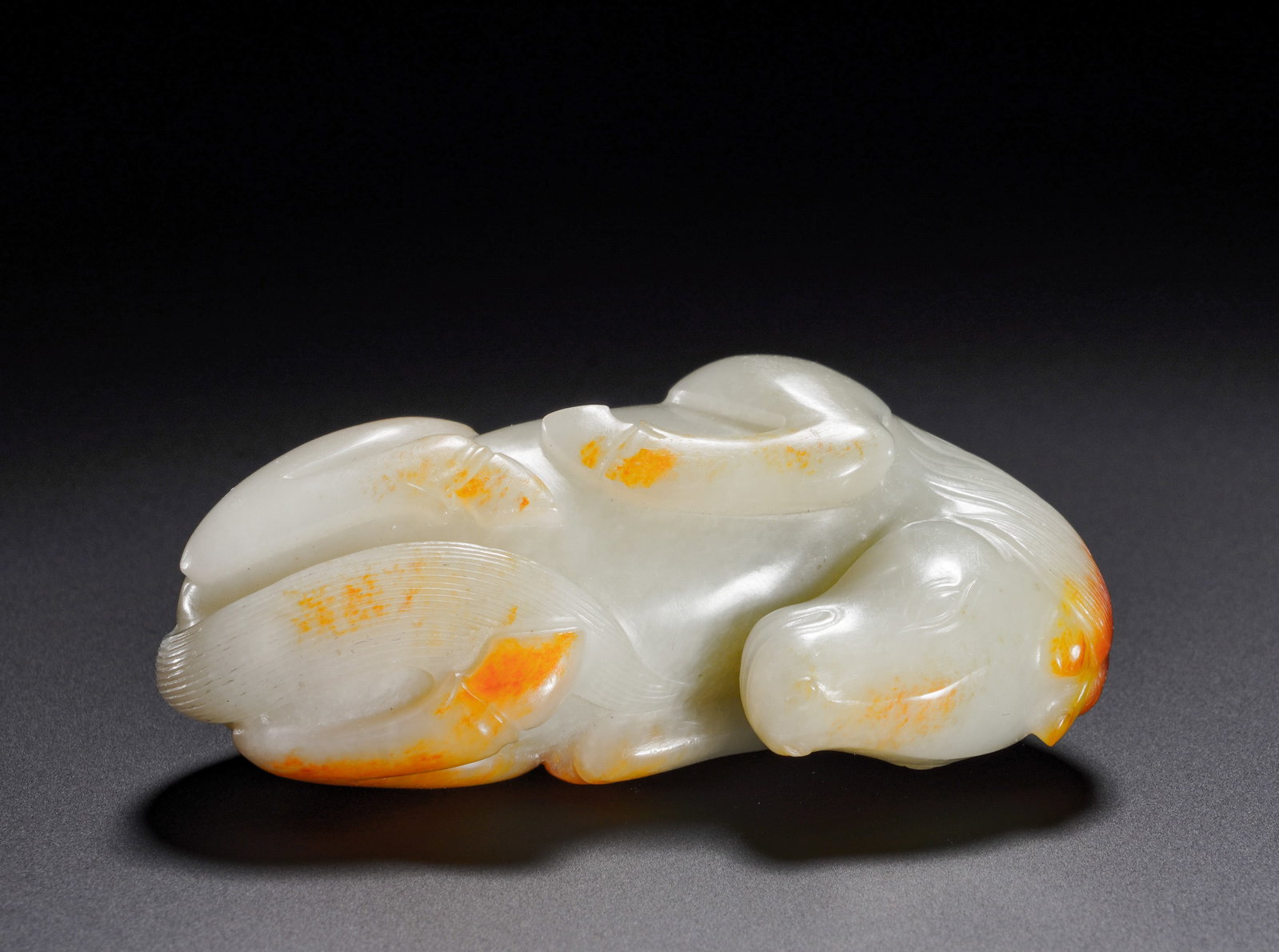QING DYNASTY HETIAN JADE RECLINING HORSE HANDLE PIECE: Qing Dynasty Hetian white jade recumbent horse handheld ornament. The jade bears fine smooth texture with natural red suffused skin pigment cleverly distributed on the head and hooves. The horse lies 