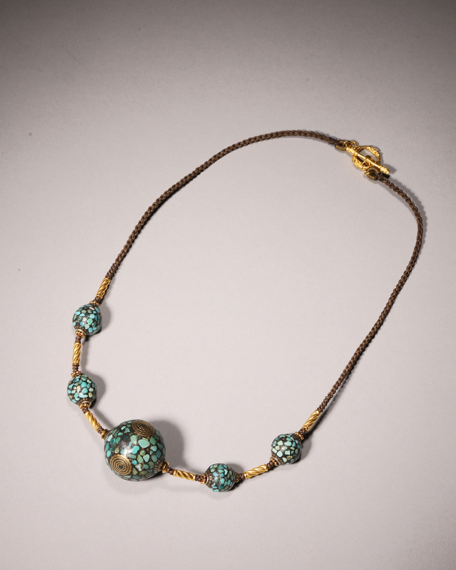 An 18th-Century 24K Gold Inlaid Turquoise Antique Bead Necklace: This antique necklace dates back to the 18th century, with five beads inlaid with natural turquoise fragments. The central bead is decorated with double spiral 24K gold ornaments, paired with twisted 