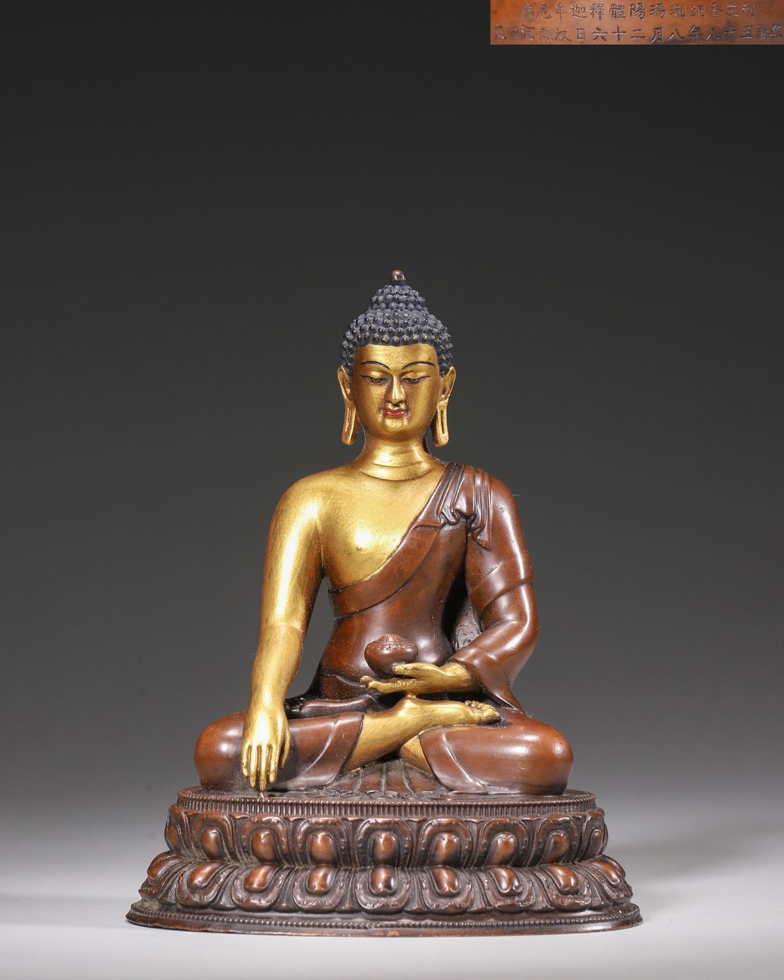 Qing Dynasty, Palace-Made Partially Gilt Bronze Statue of Shakyamuni Buddha, Qianlong Period: A palace-made partially gilt bronze statue of Shakyamuni Buddha from the Qianlong period. The Buddha sits on a lotus throne with a compassionate expression. The statue bears a dated inscription, indic
