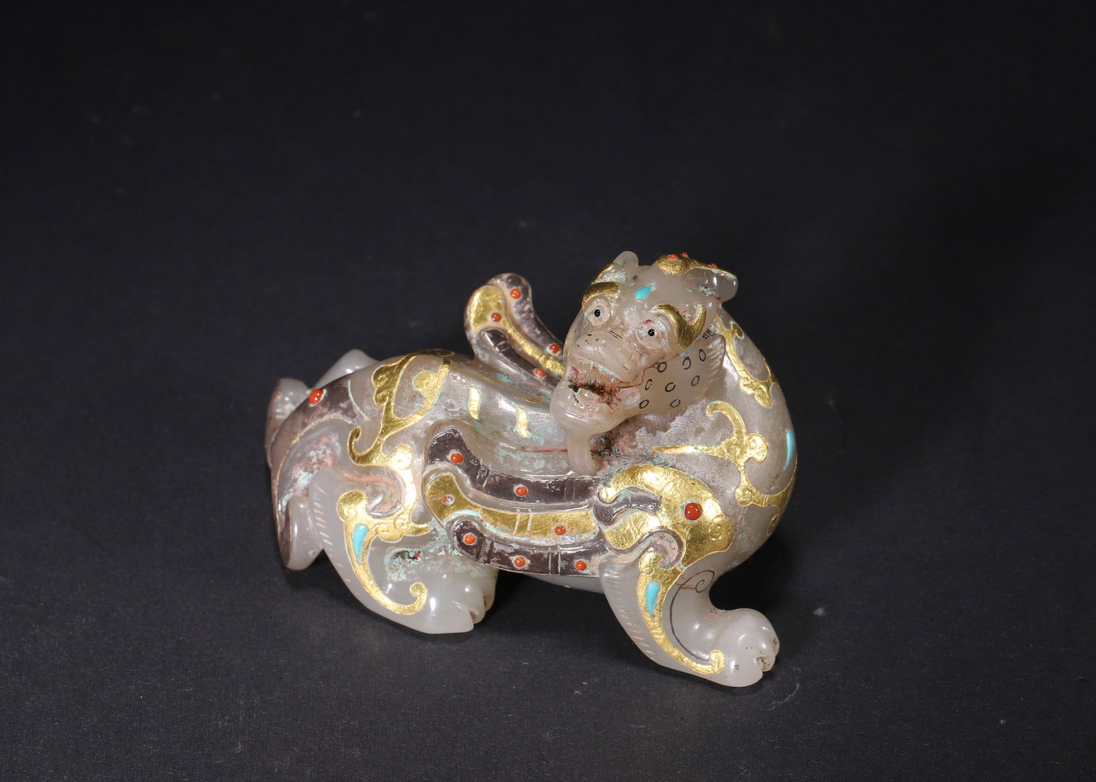Han Dynasty, Hetian White Jade Winged Beast Ornament Inlaid with Gold and Silver: Recumbent winged beast fully carved from Han Hetian white jade, covered with burial earth and bronze patina. Scroll cloud wings outlined by gold and silver inlay, inset with turquoise and coral. Horne
