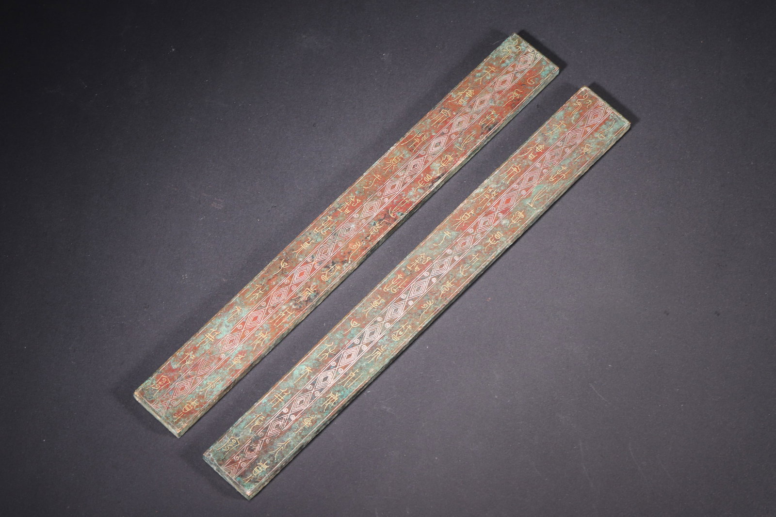 Warring States Period, Gold and Silver Inlaid Bronze Rulers with Four Divine Beasts: A pair of Warring States period bronze rulers, finely crafted with gold and silver inlay and turquoise. One side features ancient characters inlaid in gold with geometric patterns; the other depicts t
