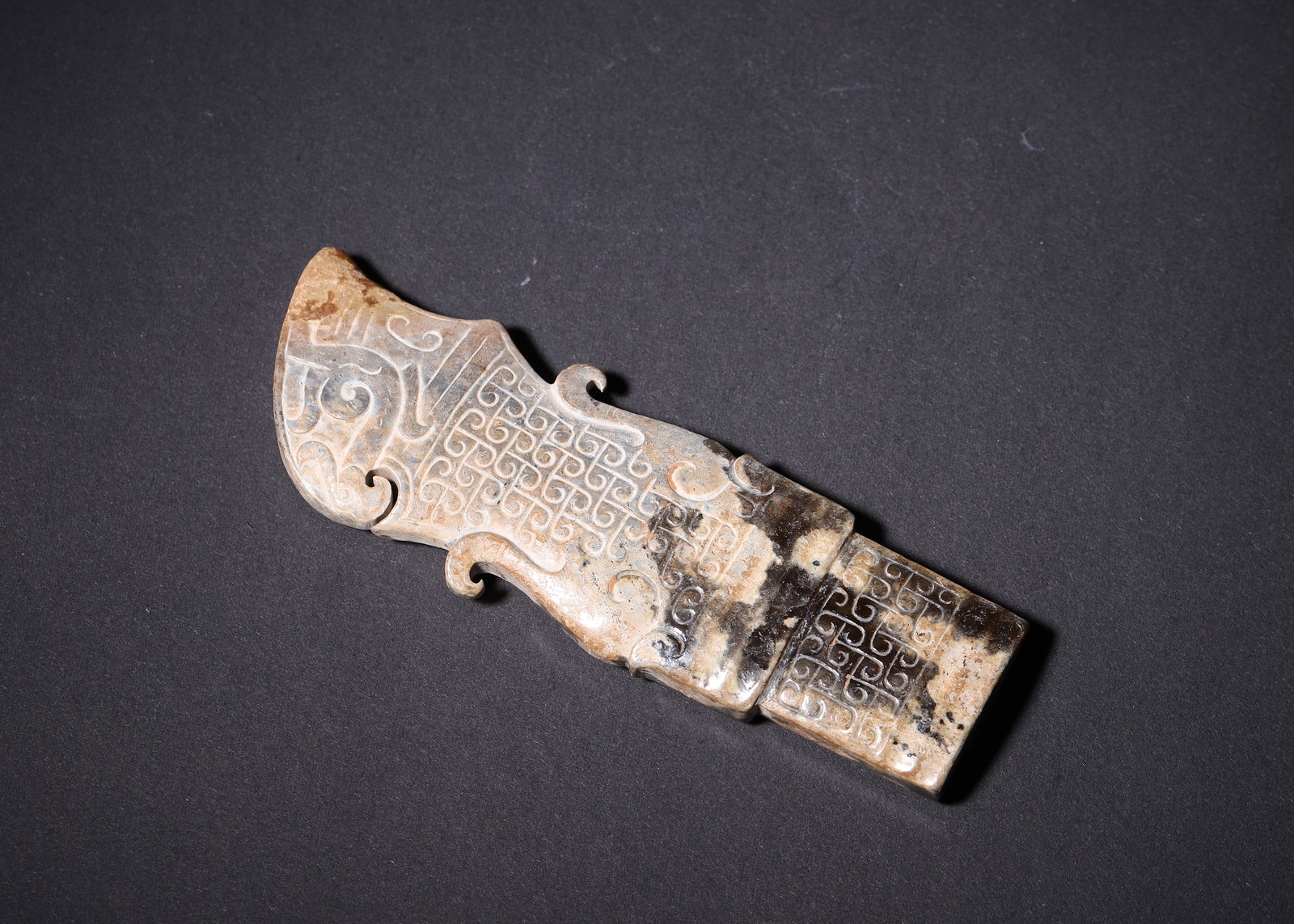 Warring States Period, Jade Phoenix-Head Blade Pendant with Cloud Pattern: A carved jade blade pendant of Warring States Period. Carved phoenix motif at blade head, dense cloud thunder patterns covering surface, symmetrical cloud flanges on sides. Deep mineralized earth incl