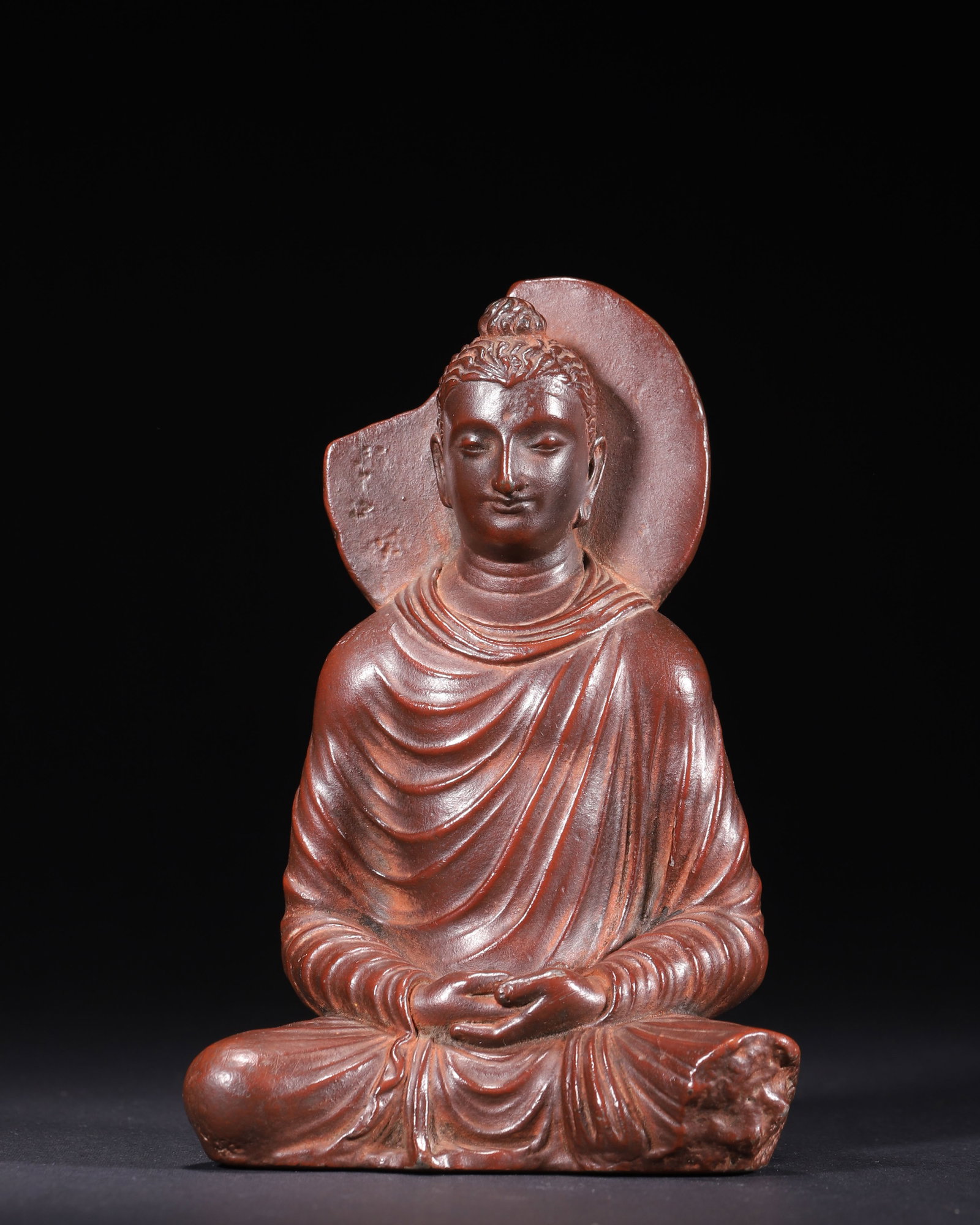 Terracotta Seated Sakyamuni Buddha, Gandhara Kushan Period (1st-5th Century AD): Ancient terracotta Buddha of Gandhara Kushan Dynasty (1st-5th century AD). Molded fine red clay, Buddha seated full lotus with dhyana mudra, Hellenistic realistic facial features, spiral ushnisha, lay