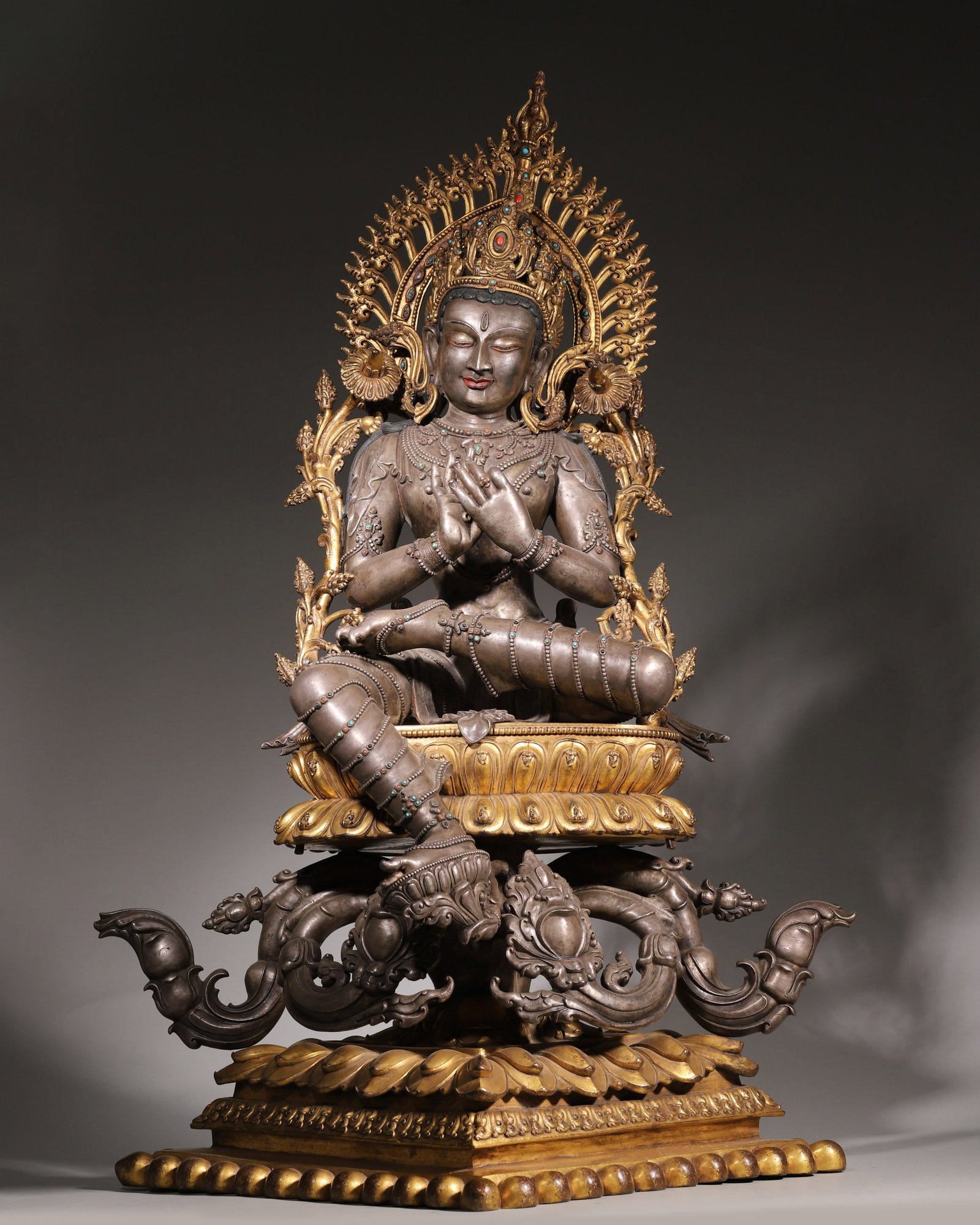 Qing Dynasty, Silver-Inlaid Gemstone Statue of Tara with Gilt Bronze Backlight and Base: This Qing Dynasty Tara statue is exquisitely crafted of silver, with a detachable gilt bronze backlight and base. It sits in a relaxed posture with hands in mudra and a benevolent look, adorned with i