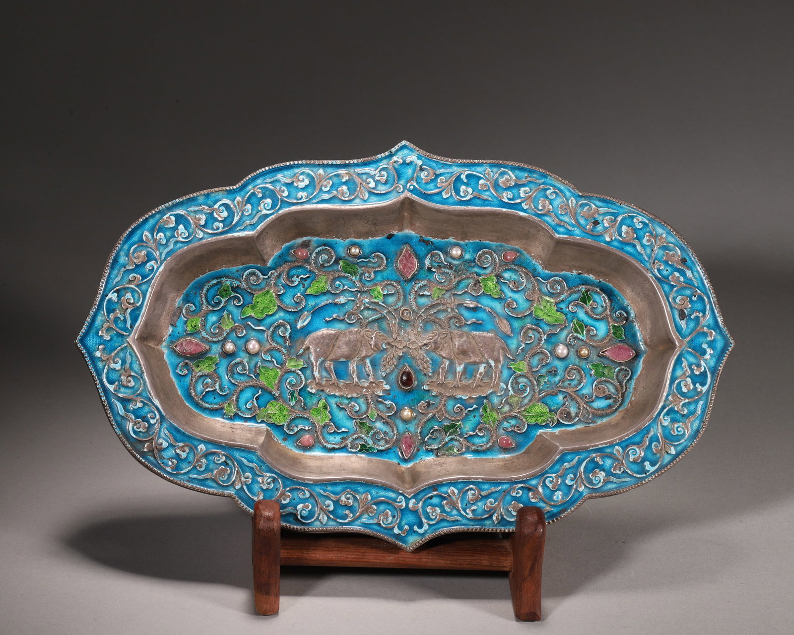 Qing Dynasty, Silver Enameled Lobed Dish with Gem-Inlaid Double Ox Motif: This lobed dish is crafted from pure silver with vibrant enamel. The center features a carved double ox motif inlaid with pearls and gems, surrounded by enamel scrollwork. The back is engraved with do