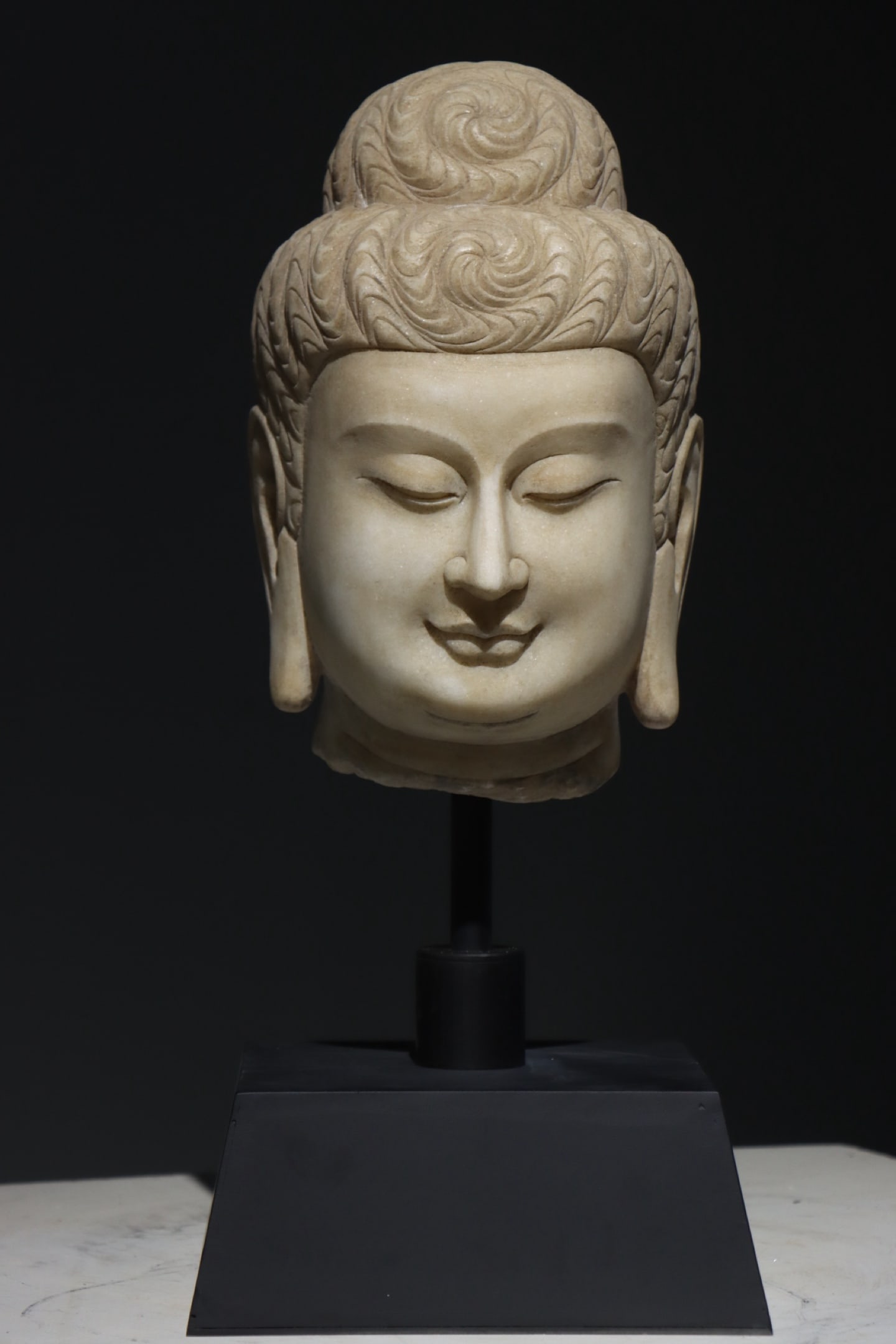 Northern Qi Dynasty, Fine White Marble Head of Buddha: This fine white marble head of Buddha, from the Northern Qi Dynasty (6th century AD), is exquisitely carved. Its round face, downcast eyes, and gentle smile embody the serene compassion characteristic