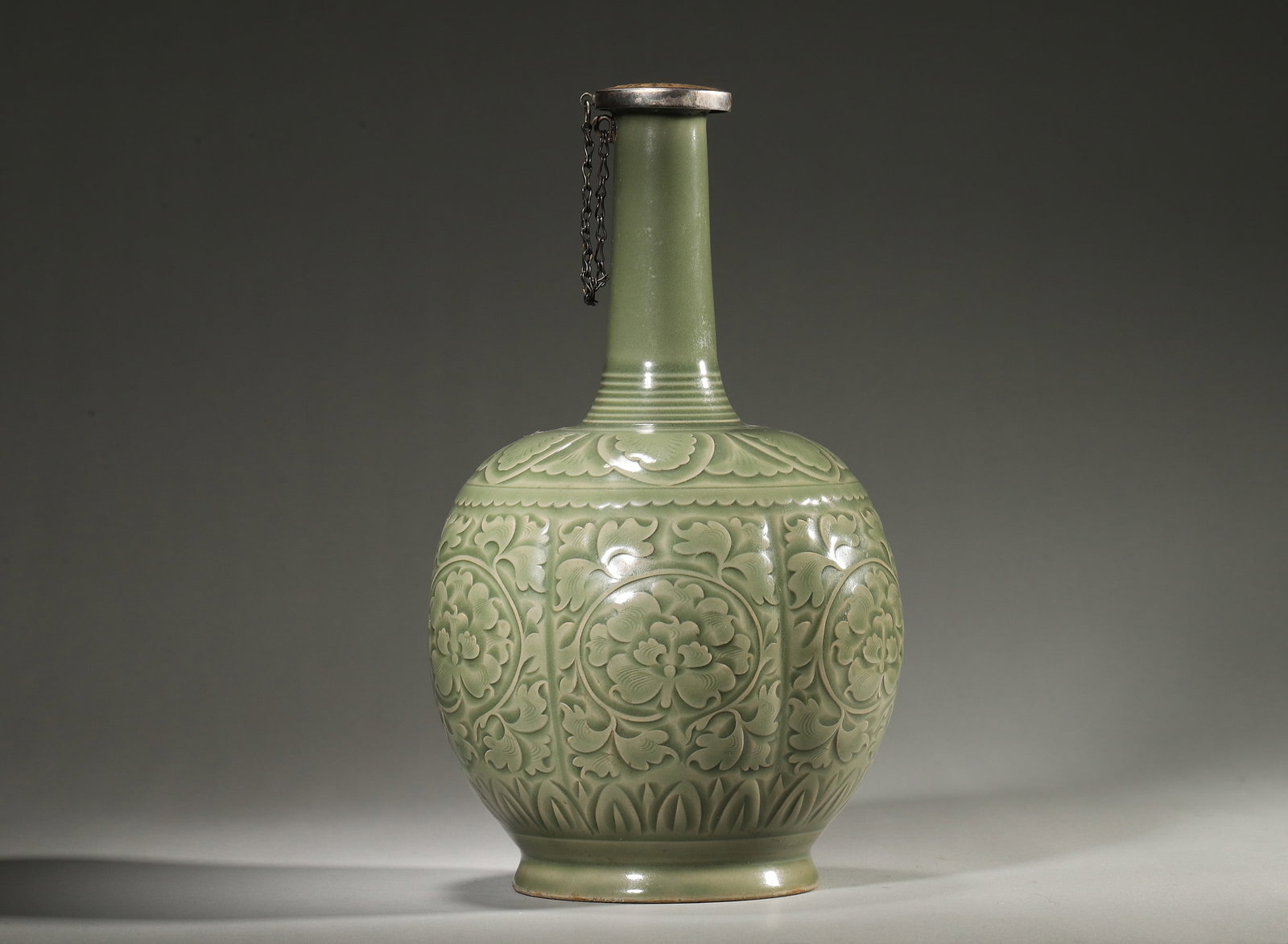 Yaozhou Celadon Carved Long-Neck Vase, Song Dynasty, 960-1279: Long neck with bow-string patterns,melon-shaped body covered by celadon glaze. Carved peony scrolls and lotus motifs,exposed foot base,lustrous glaze surface. Dimensions: Diameter: 16cm (6.3in), Heigh