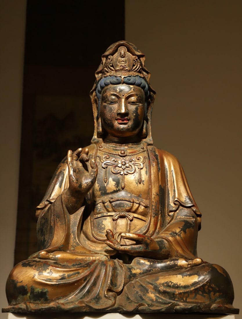 Gilt-Lacquered Bronze Seated Guanyin Statue, Ming Dynasty (1368-1644): Gilt-lacquered bronze Guanyin in full lotus posture. Diadem bears small carved Buddha. Wears elaborate neck ornaments. Right hand in teaching mudra. Gilding partially worn, four-petal floral mark on b