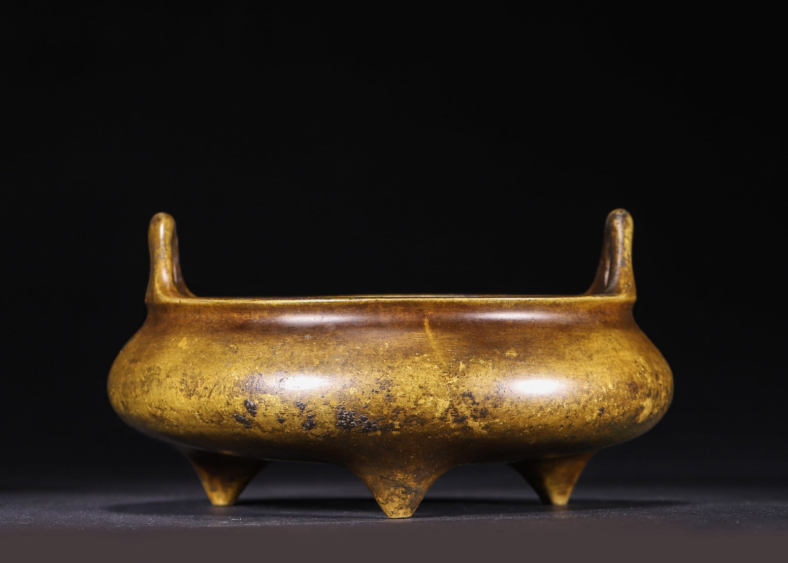 Qing Dynasty, Bronze Tripod Censer with Upright Loop Handles, Gui You Mark: A bronze tripod censer of Qing Dynasty with two upright arched handles and three pointed feet. It bears the seal mark "Gui You Zhong Yue Jing Zhi" on base, covered with aged golden patina, with ancien