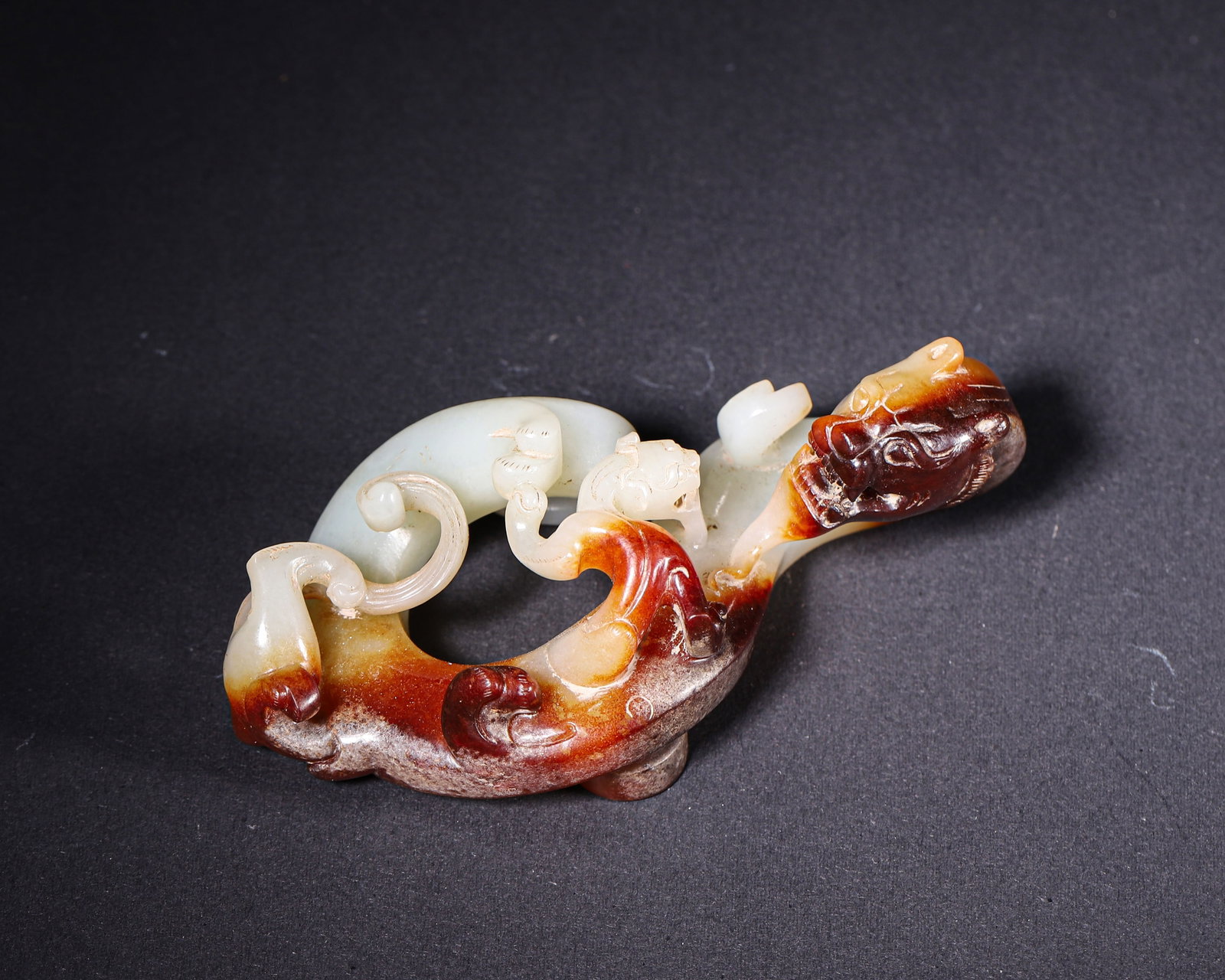 Han Dynasty, Hetian Jade Openwork Belt Hook with Dragon and Cub Motif: Carved from Hetian jade with reddish brown and grayish black patina. Openworked dragon and cub design. Round knob on reverse, incised seal script marks. Robust archaic carving. Dimensions: Length: 11.