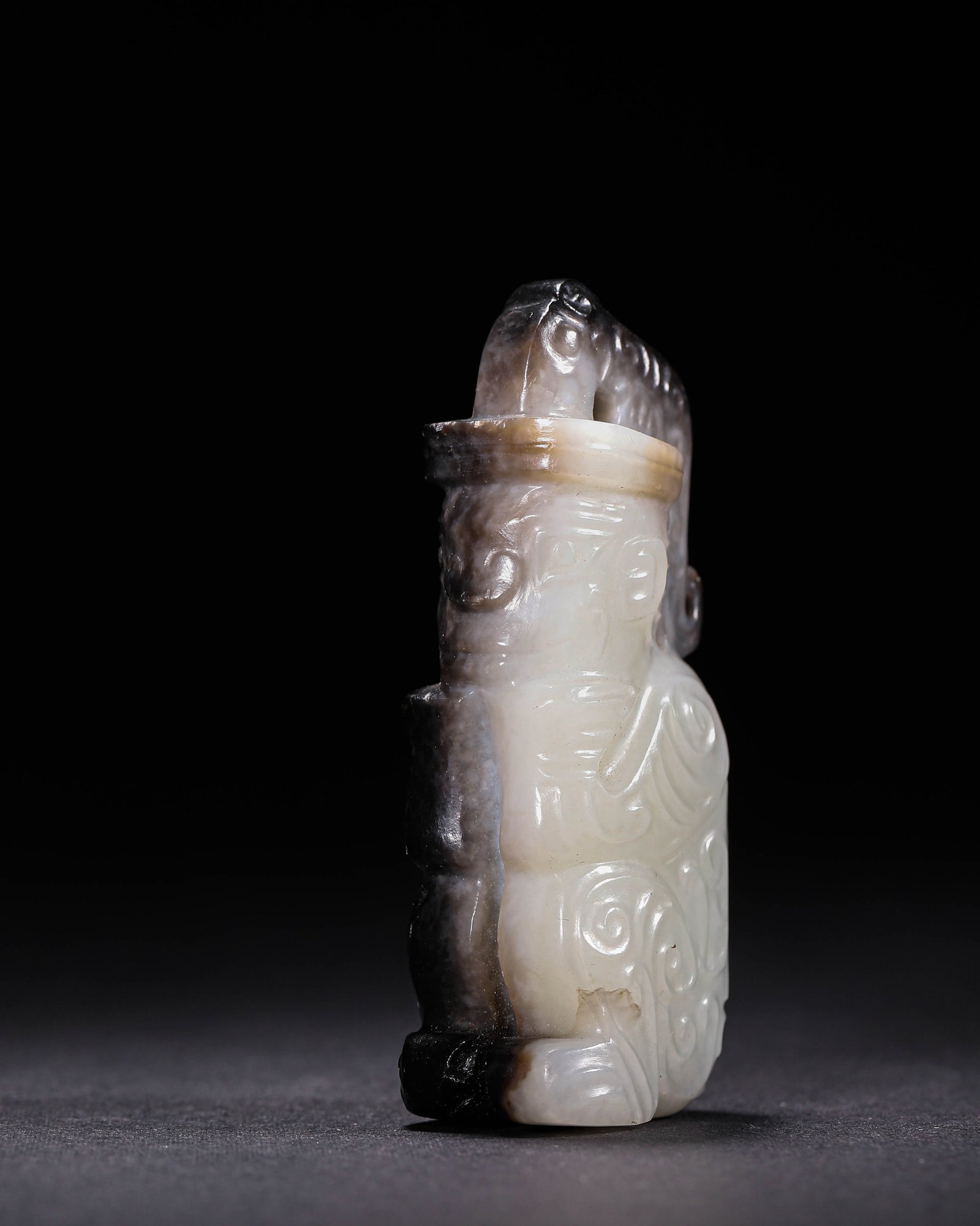 Hetian Jade Figure Pendant with Black Suffusion, Shang Dynasty (1600 BC-1046 BC): Hetian jade with heavy black-brown suffusion. A kneeling human figure with headdress, scroll patterns, ancient incised symbols and piercing holes, archaic carving and aged patina, a Shang jade pendant
