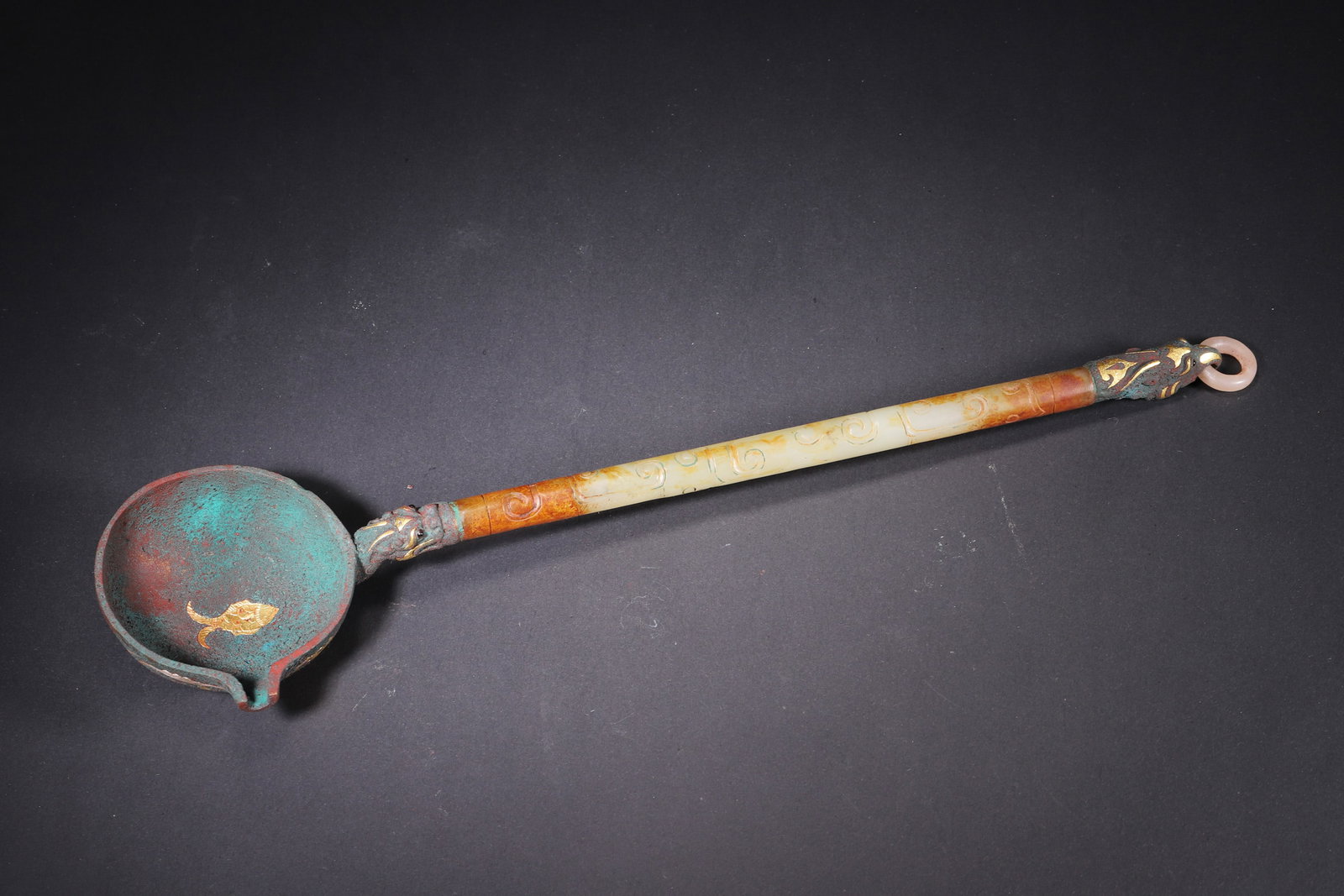 A Warring States Bronze Ladle with Gold and Silver Inlay and Jade Handle: This Warring States bronze ladle features a jade handle with cloud patterns and exquisite gold and silver inlay with auspicious beast motifs. It embodies the superb craftsmanship and noble aesthetic o