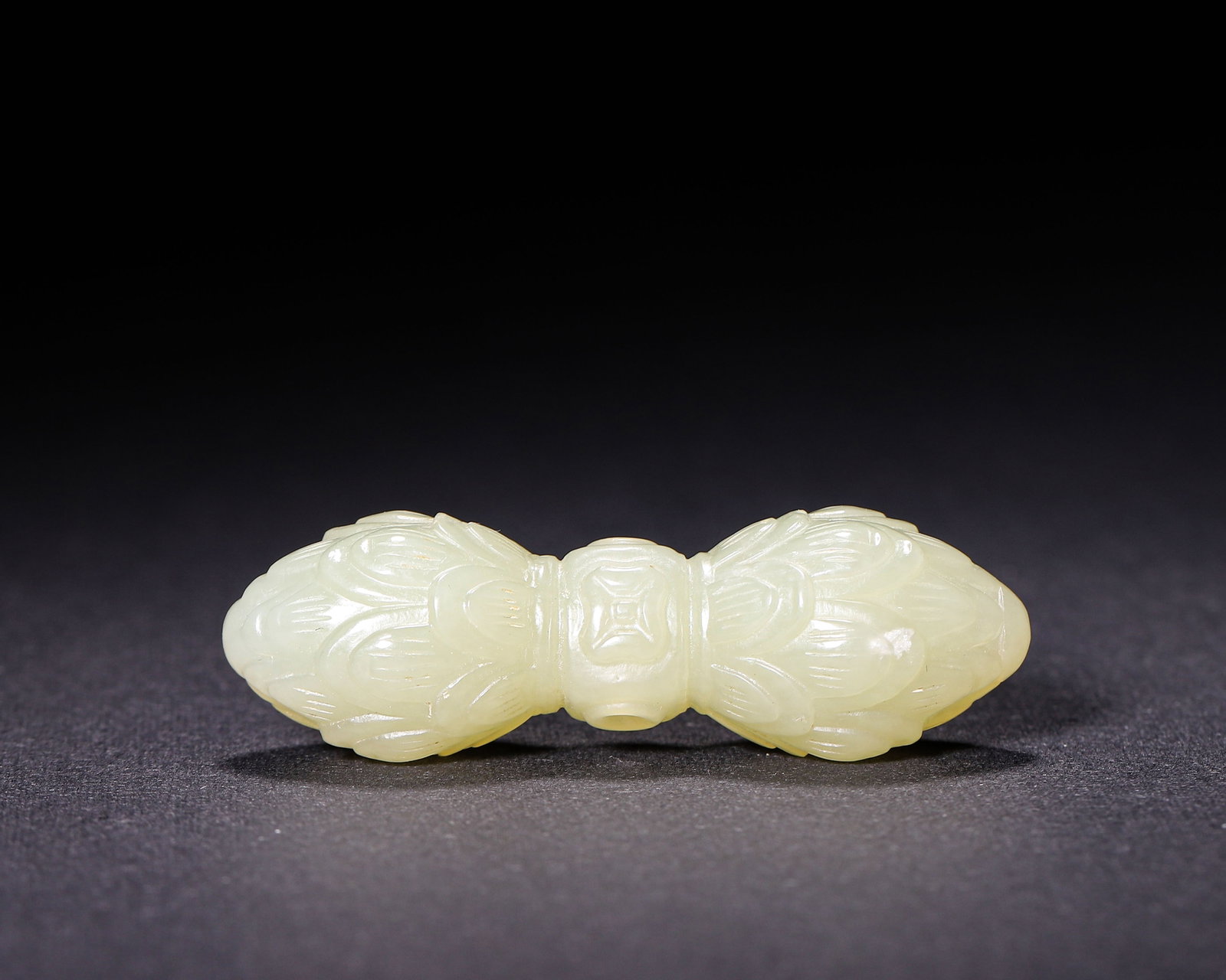Nephrite Bead Carved with Double Lotus Pattern, Qing Dynasty (1644 1912 CE): Celadon nephrite bead with double lotus bud ends. Fully carved lotus petal motifs, central piercing for threading. Smooth jade texture, well executed carving, Qing dynasty personal ornament. Dimension