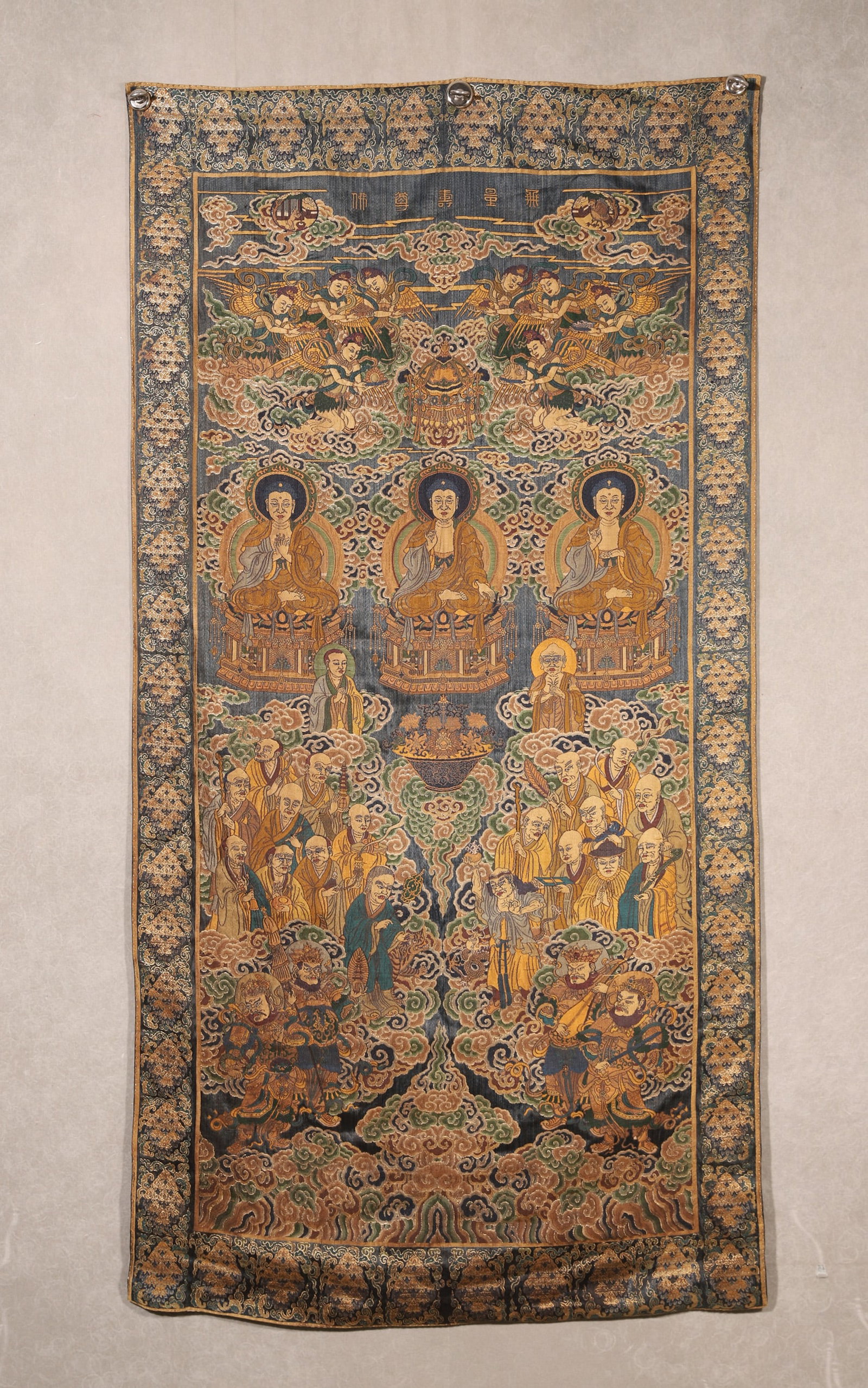 A Qing Dynasty Brocade Hanging Scroll of Amitayus Buddha Assembly: A Qing Dynasty brocade hanging scroll depicting Amitayus Buddha assembly, inscribed with "Infinite Life Buddha??. Features three central Buddhas, arhats, protectors and celestial beings woven with fin