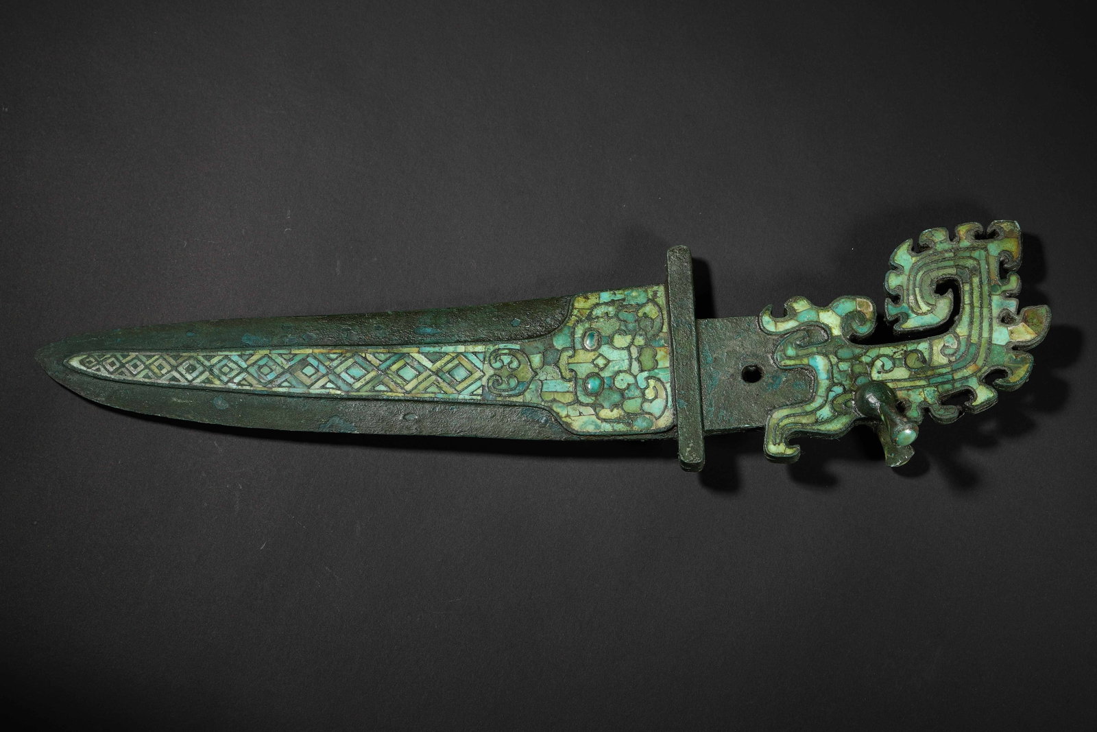 Western Zhou Dynasty Turquoise-Inlaid Bronze Short Sword: C. 1046-771 BCE. Sword Guard & Handle Inlaid with Turquoise Decorations of Taotie & Geometric Patterns; Intricate Craftsmanship. A Model of Decorative Art in Western Zhou Bronze Weaponry. It Witnesses