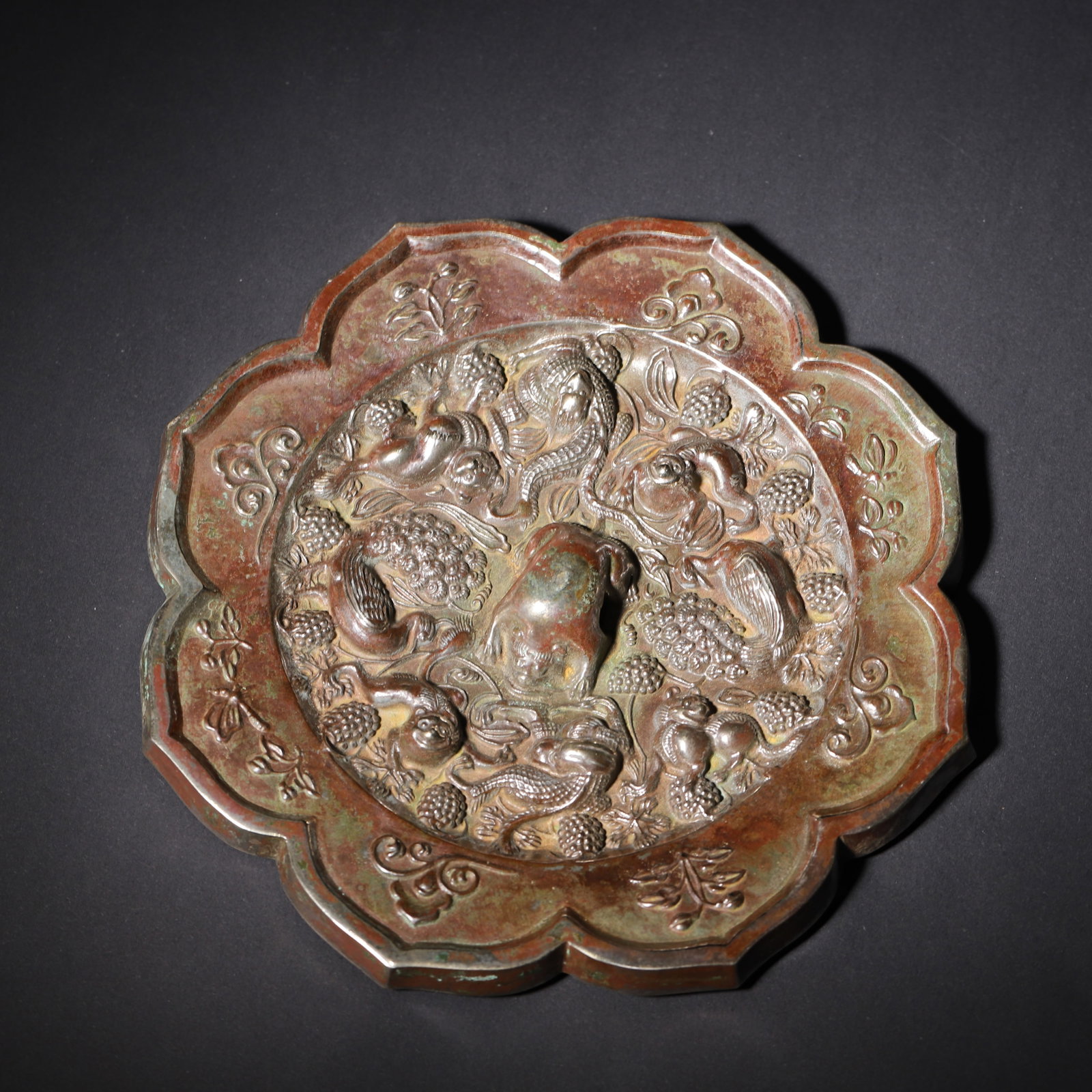 Tang Dynasty, Bronze Lobed Mirror with Sea Beasts and Grapevine Motifs: Tang eight-lobed bronze mirror with high relief. Central crouching beast knob surrounded by sea beasts, birds, serpents and interwoven grapevines. Each lobe of the rim bears shallow carved floral and 
