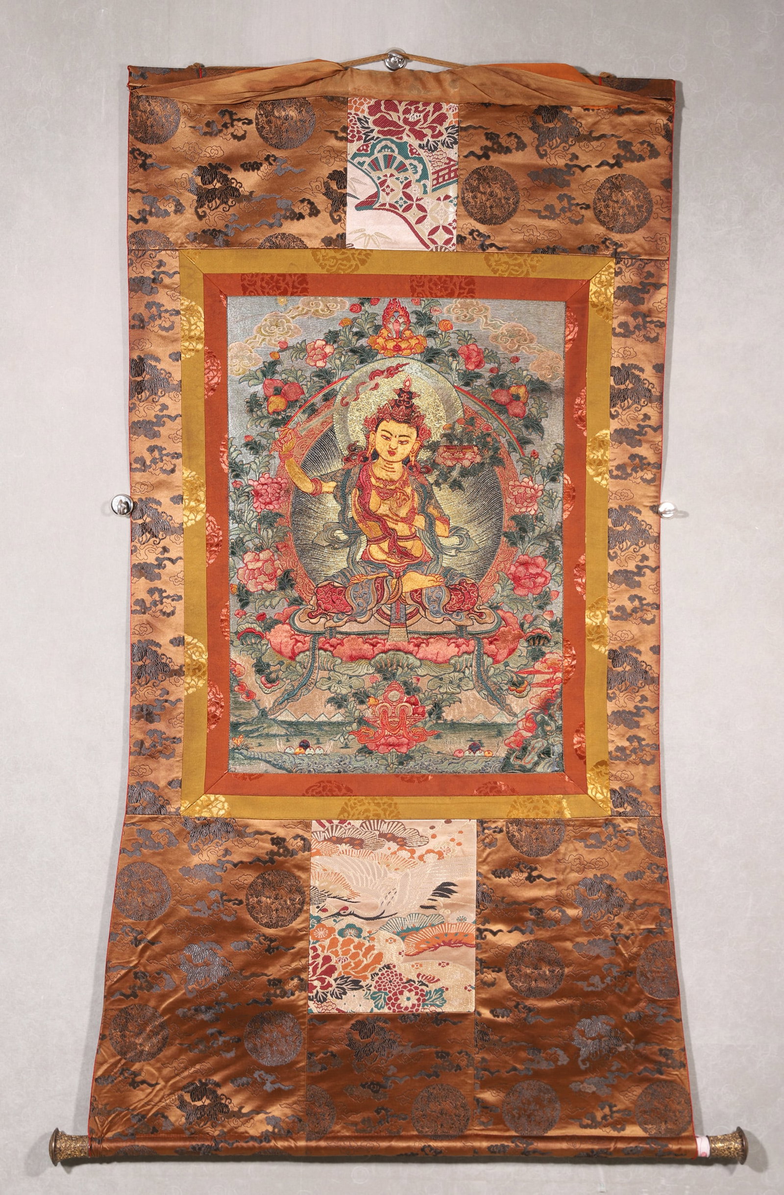 Qing Dynasty, Embroidered Thangka of Manjushri: A Qing Dynasty embroidered thangka of Manjushri, the Bodhisattva of Wisdom. Meticulously crafted with fine embroidery and gold threads, depicting the seated deity holding a sword and scripture, surrou