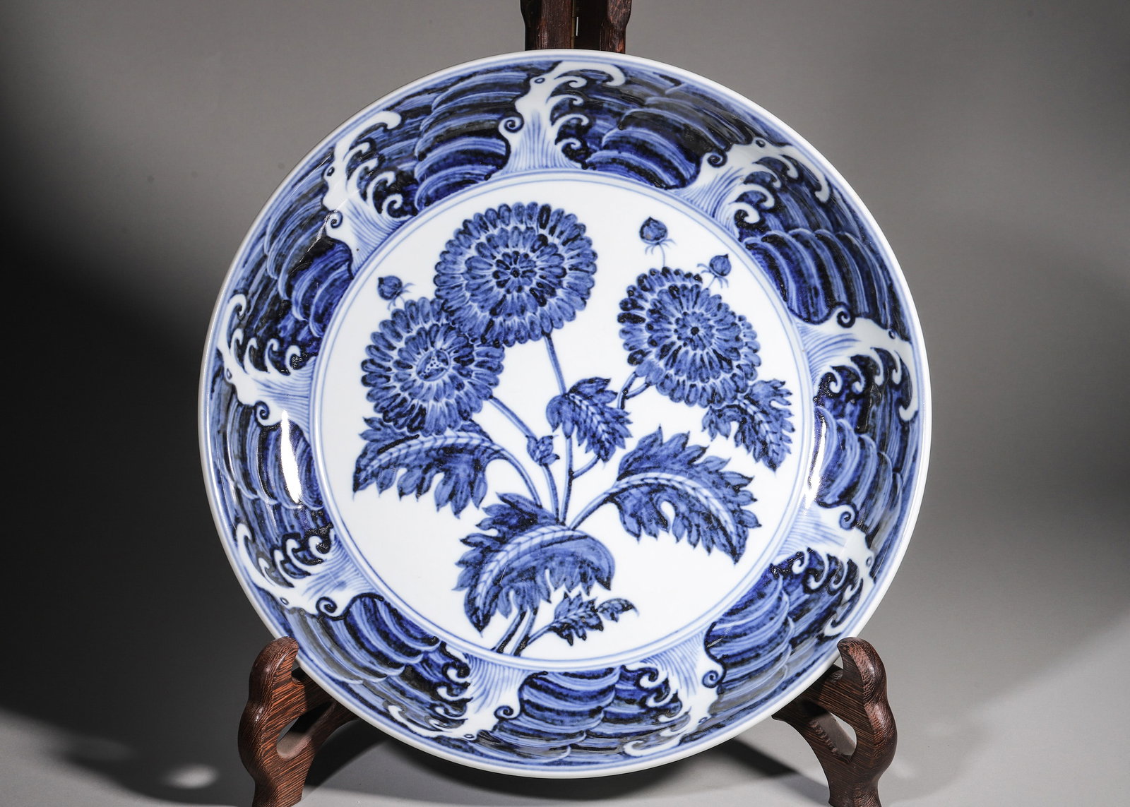 Ming Dynasty, Blue and White Chrysanthemum and Fruit Charger, Xuande Period: Ming Xuande mark and period. Shallow rounded charger with unglazed base. Interior central chrysanthemum spray, bordered by rolling waves. Exterior painted with pomegranate, peach and grape for abundan