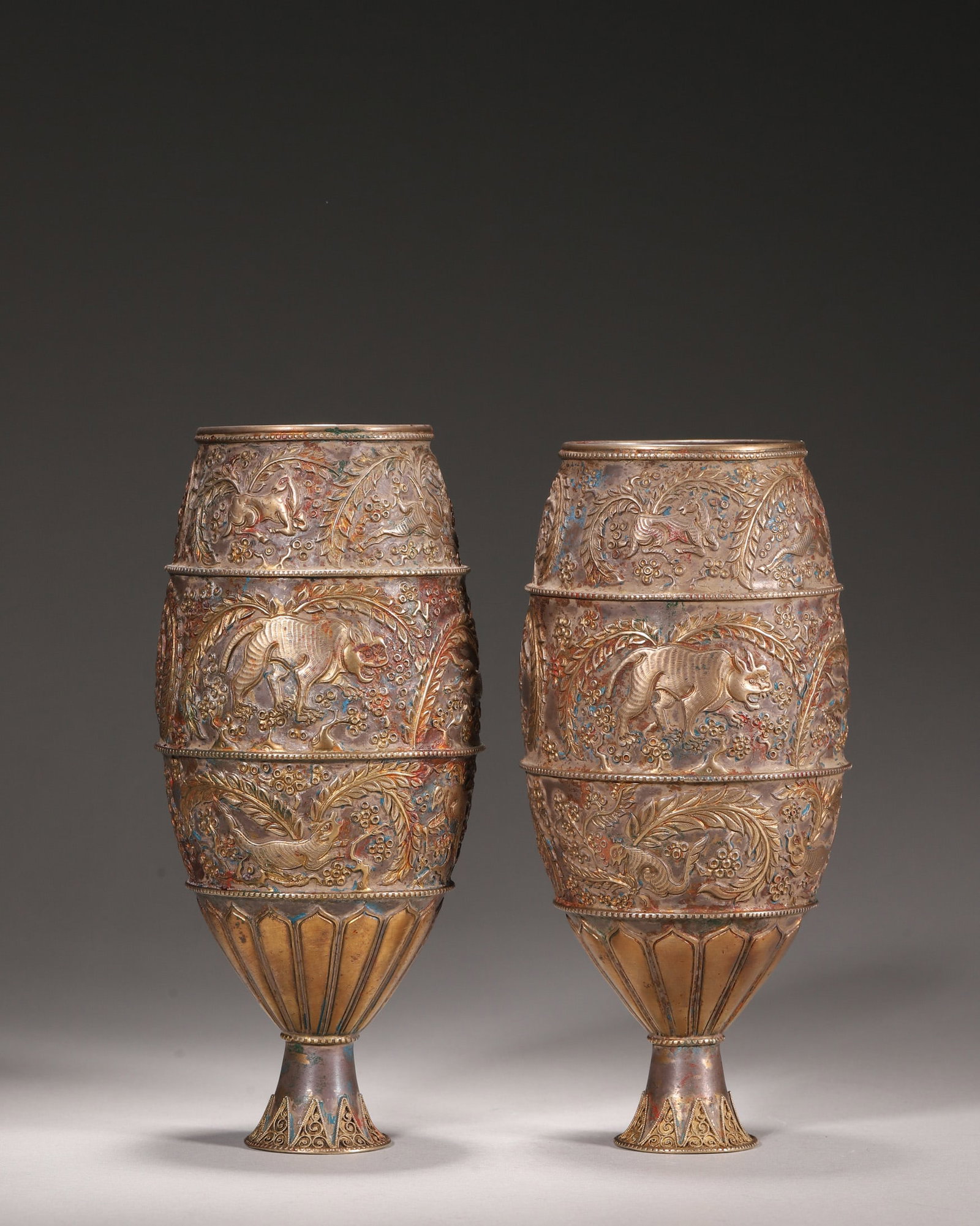 Tang Dynasty, Pair of Partially Gilt Silver Stem Cups with Auspicious Beasts: A pair of Tang Dynasty silver partially gilt stem cups, divided into three sections with engraved and gilt auspicious beasts and flowers. With lotus-petal feet, they reflect the superb craftsmanship o