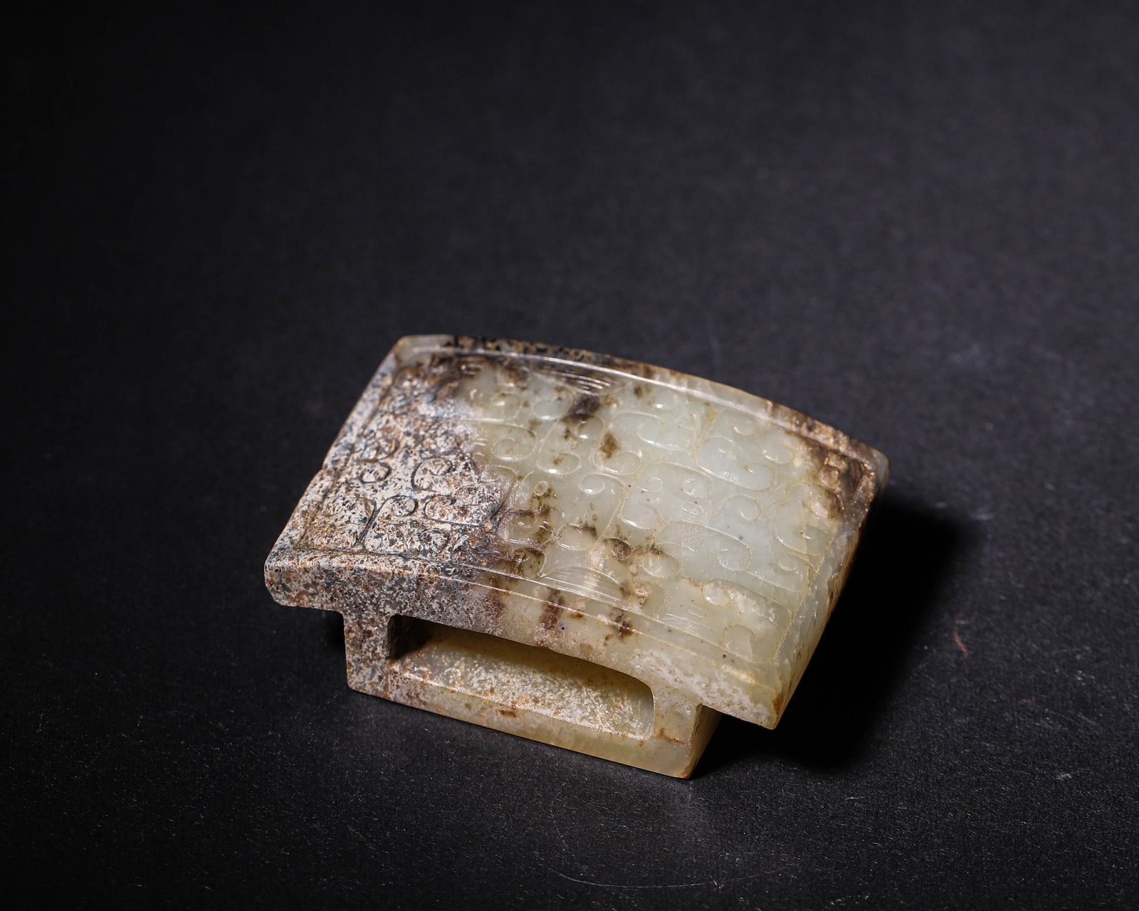 Hetian Jade Sword Slide with Cloud-Scroll Pattern, Han Dynasty (202 BC-220 AD): Hetian jade sword slide carved with cloud-scroll motifs. Partial black and earth patina, bottom slot for mounting, thick patina, Han dynasty sword fitting. Dimensions: Length: 5.2cm (2.05in), Width: 3