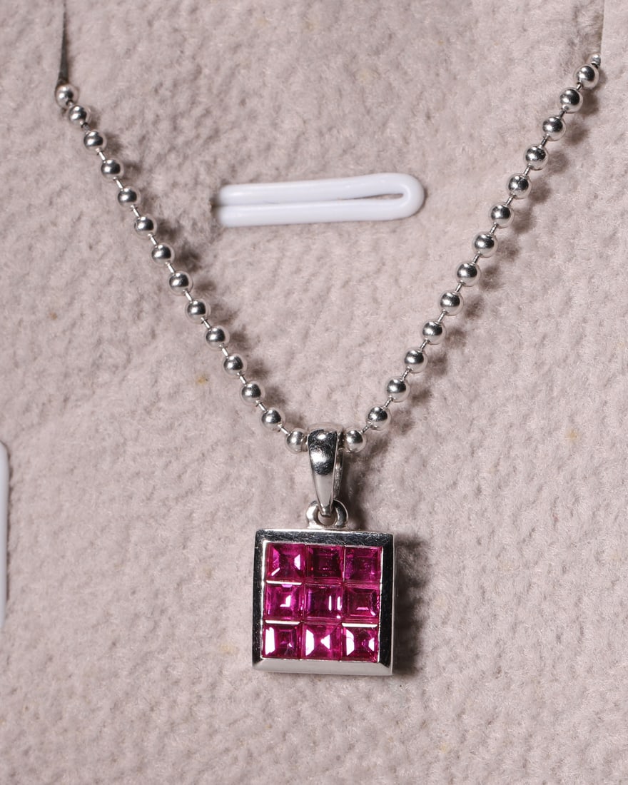 An 18K White Gold Square Nine-Stone Ruby Pendant Necklace: Vertical Drop Nine square rubies are neatly set into a square plaque with polished 18K white gold bezel. Matched with smooth bead chain, this minimalist geometric necklace is ideal for everyday wear a