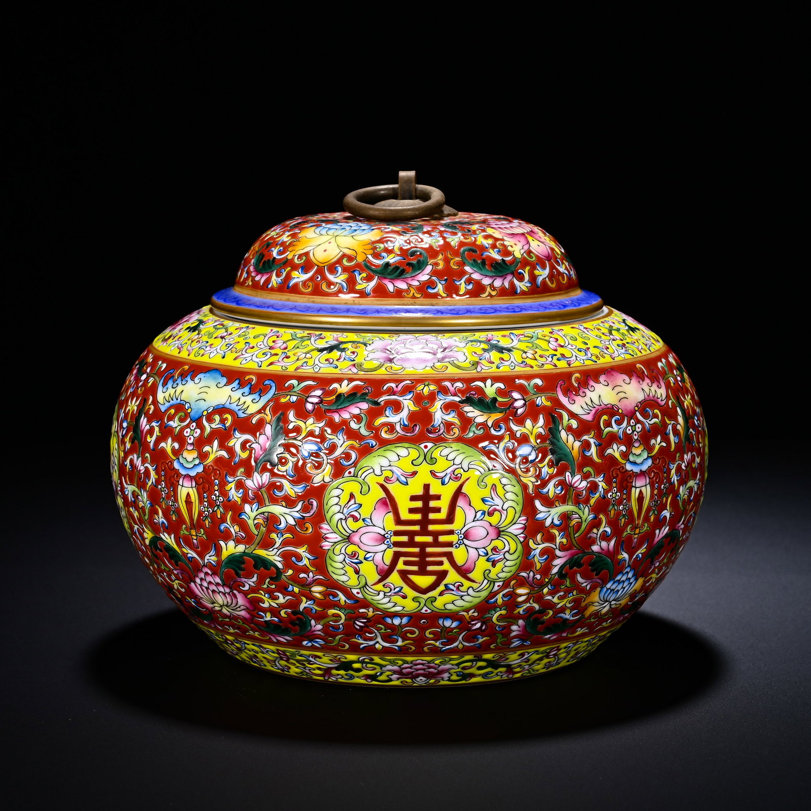 Qing Dynasty, Qianlong Period, Red Ground Pastel and Floral Longevity Character Pattern Lid Jar: A Qianlong-period covered jar with red ground, famille-rose scrolling flowers and shou-character motif. It has a plump rounded body with original lid fitted with movable bronze ring knob. The red grou