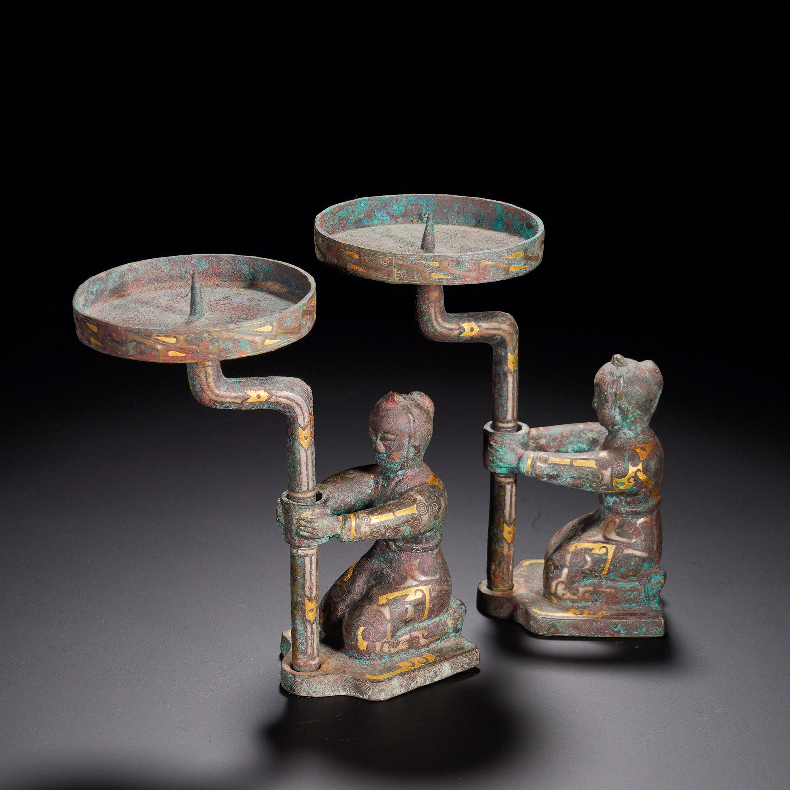 Han Dynasty, Bronze Inlaid Gold Kneeling Lamp (Pair): A pair of bronze lamps dating to the Han dynasty. Cast in bronze and decorated with gold-inlaid patterns, the surfaces are covered with layered turquoise-green and reddish-brown patina and heavy aged 