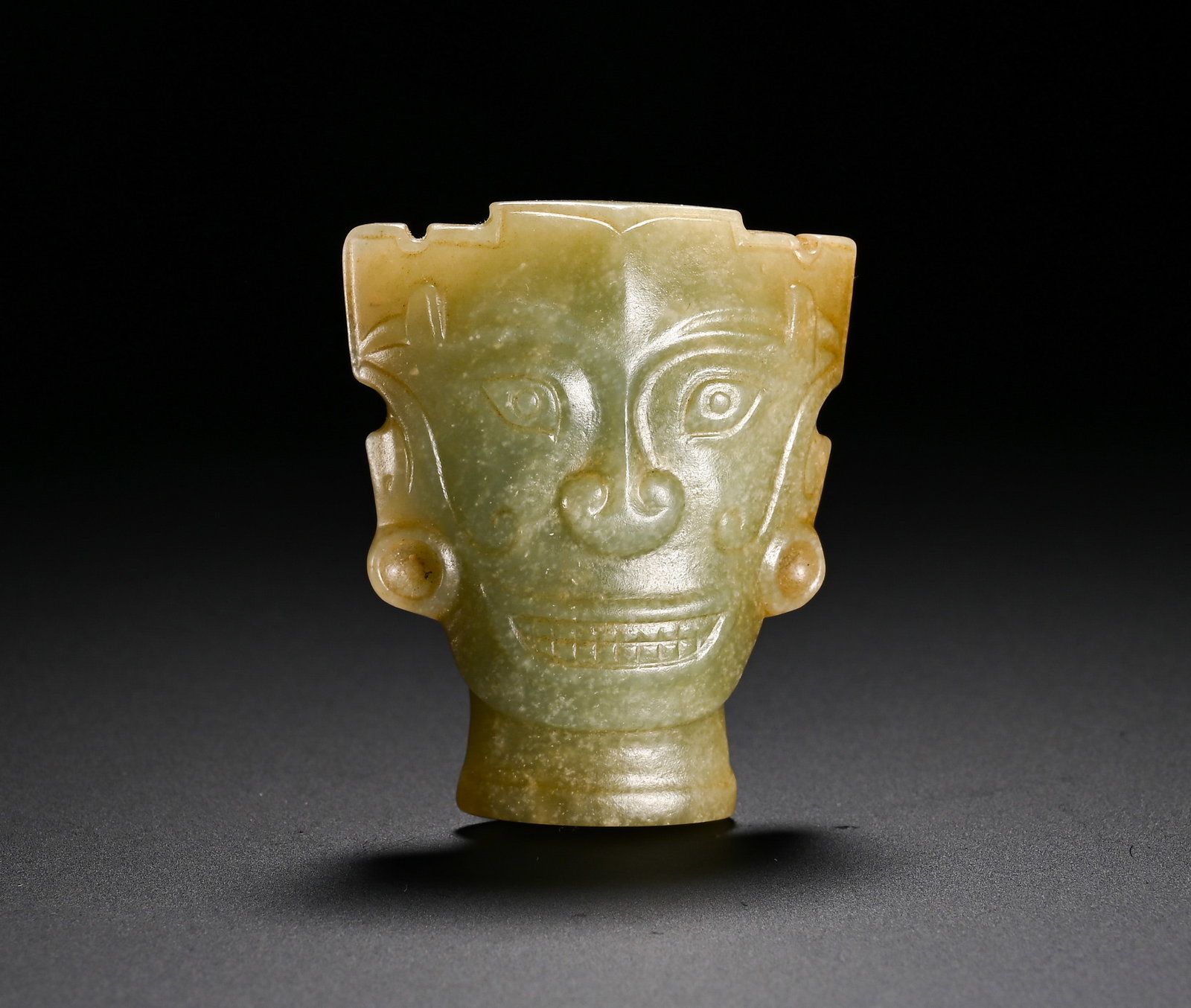 Shang and Zhou Dynasties, Hetian Jade Divine Head Pendant: Shang-Zhou Dynasty Hetian jade divine human head pendant. The jade bears a bluish mild tone. The deity??s face is delineated by incised fine lines with round eyes, curled nasal ornamentations and dist