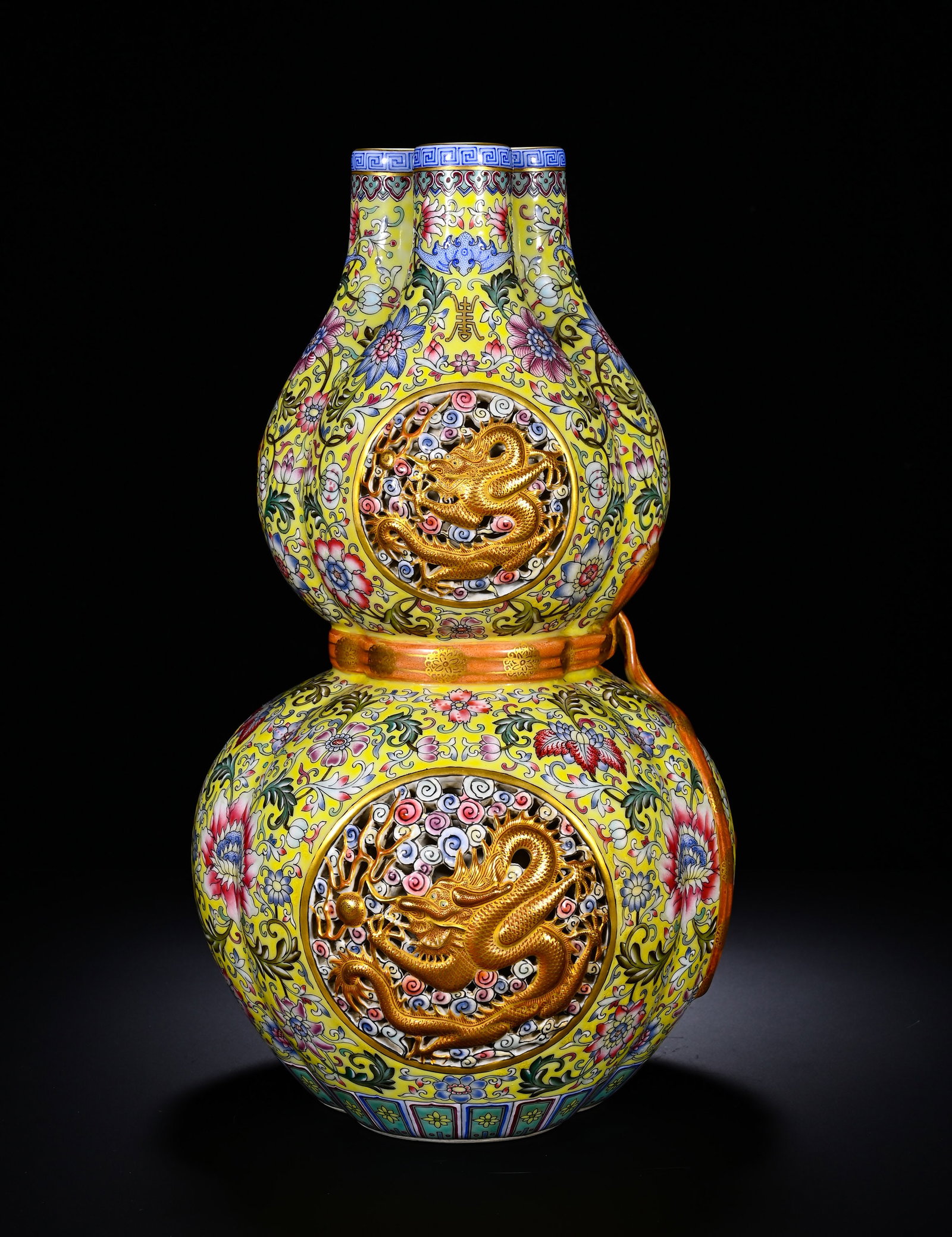 Qing Dynasty, Yellow-Ground Pastel Flower-Shaped Gourd Vase from the Qianlong Period: A Qianlong-period triple-neck gourd vase on yellow ground, with famille-rose scrolling flowers, openwork gilded-dragon panels and relief ribbon ornament. Three-tube mouth, double-gourd shape with gild