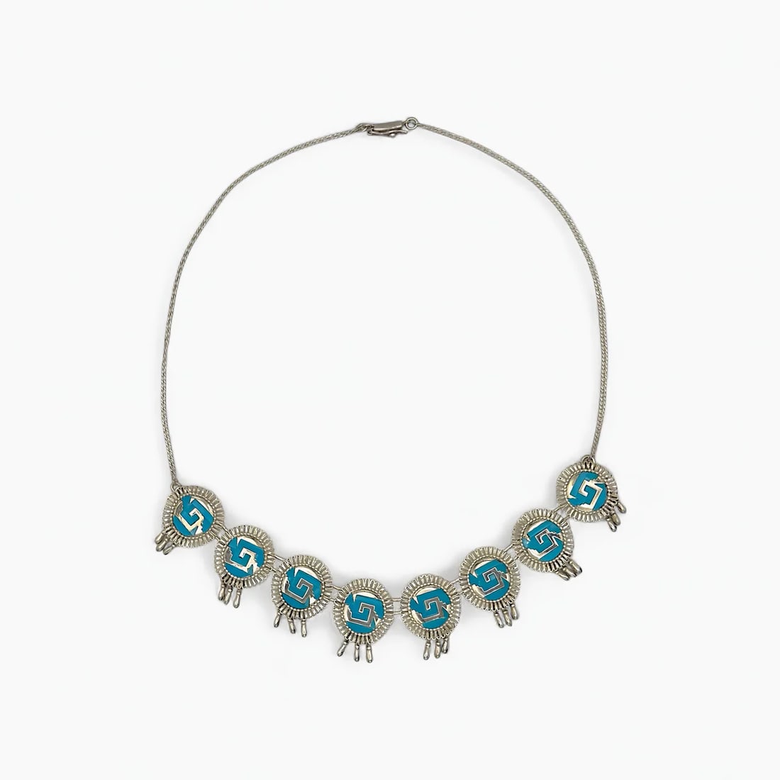 "Aztec Resonance" Turquoise Necklace: Combining form, sound, and symbolism, the Aztec Resonance Necklace by Oro de Monte Albán brings movement and rhythm to ancestral design. Each medallion features a vivid turquoise inlay with a geometr