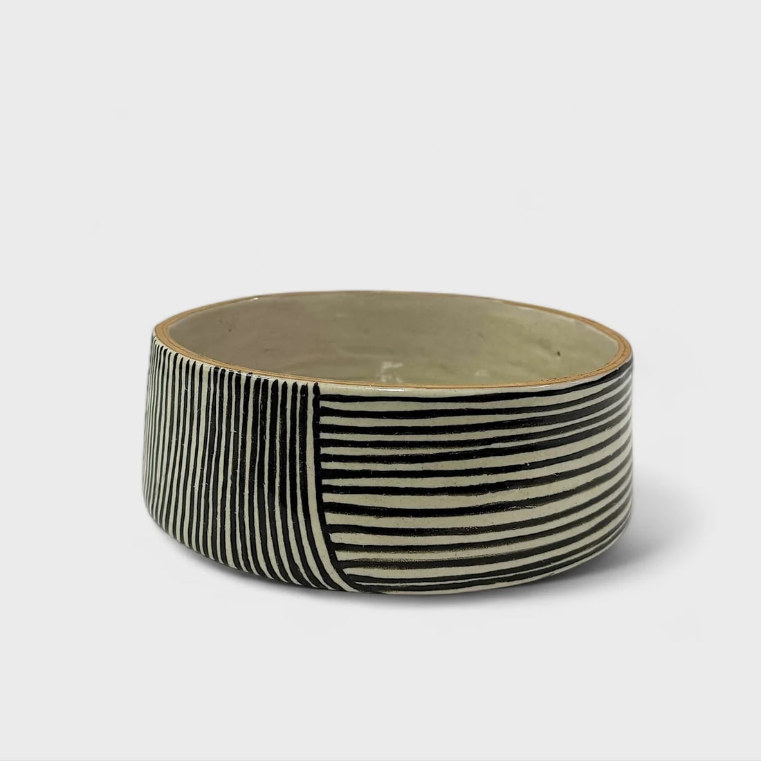 "Parallel Motion" Hand-thrown and Painted Ceramic Bowl: Talavera de la ReynaParallel Motion Bowl3.5" (h) x 10" (l) x 10" (w)3.8 lbs. Hand-thrown and hand-painted ceramic. Black-and-white linear motif.Bold, minimal, and rooted in centuries-old ceramic
