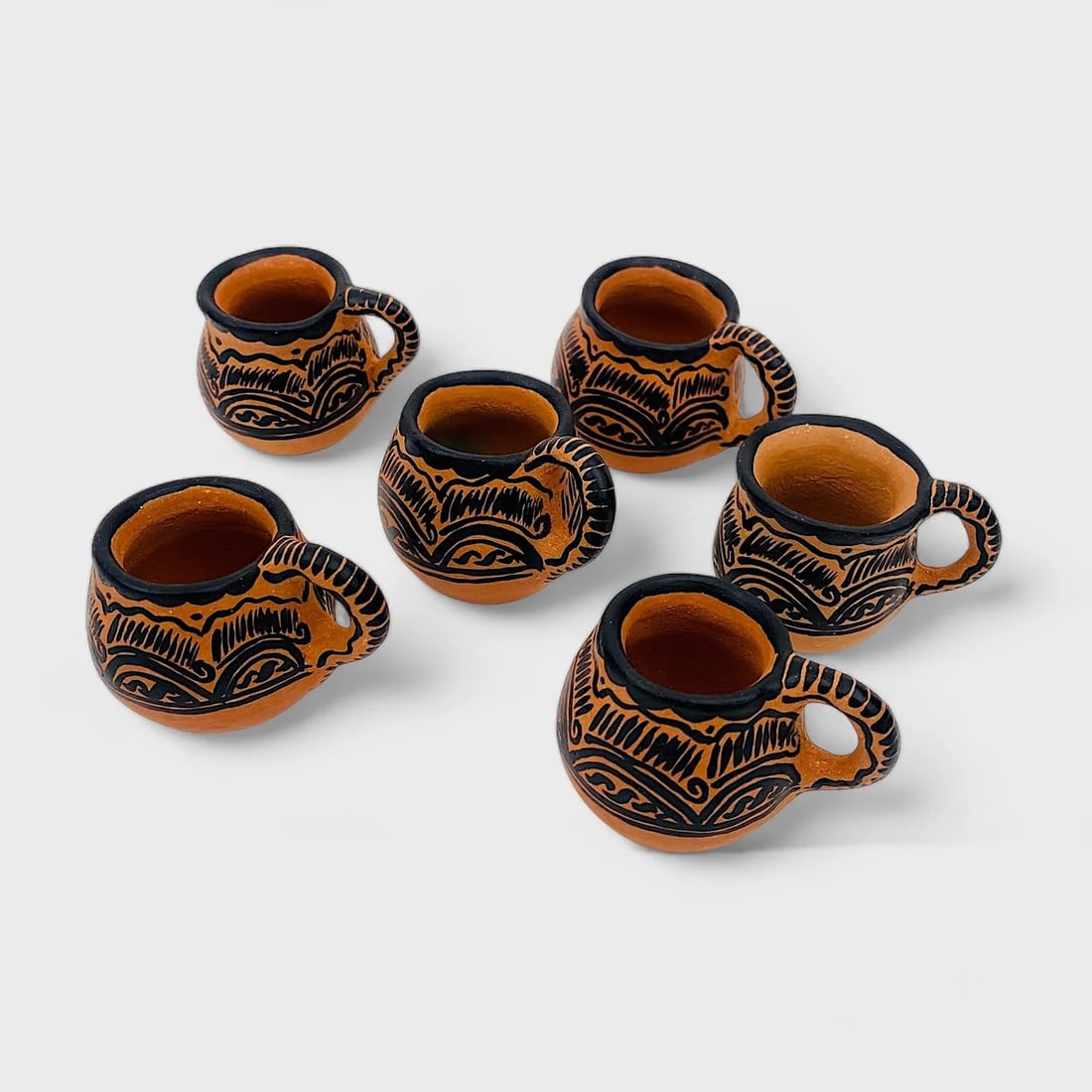 "Jaguar Mezcaleros Set" 6 Natural Clay Mugs: Albertina Lopez RamirezJaguar Mezcaleros Set (6)1.75" (h) x 2.5" (l) x 2" (w)0.4 lbs. Hand-sculpted clay with etched jaguar and botanical motifs, black slip finish.Rooted in ritual and refined in exec
