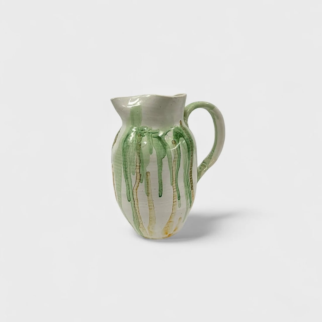 "Sierra Verde" High-fired Ceramic Pitcher: Claudia Jeronimo LopezSierra Verde Pitcher 8" (h) x 7" (l) x 4.5" (w)2.2 lbs. High-fired ceramic with green and amber flowing glaze, wheel-thrown and hand-finished. Sierra Verde Pitcher by Claudio Jer