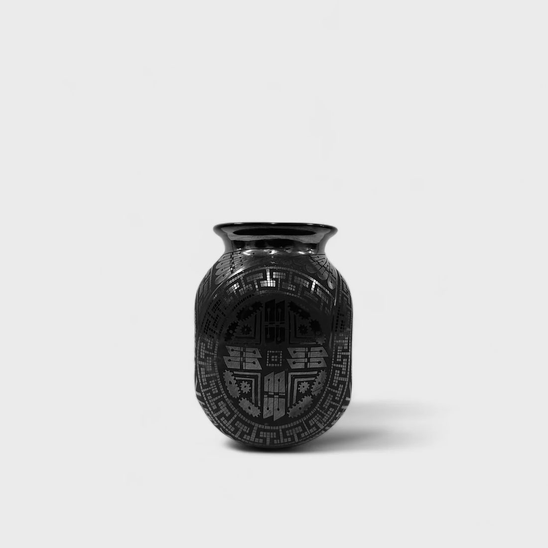 "Shadow Glyph" Hand-coiled Ceramic Vase: Eli Ortiz Shadow Glyph Vase 7" (h) x 5" (l) x 5" (w)4 lbs. Hand-coiled ceramic, polished and matte black finish with etched geometric designs. Signed. Shadow Glyph Vase by Eli Ortiz captures the drama