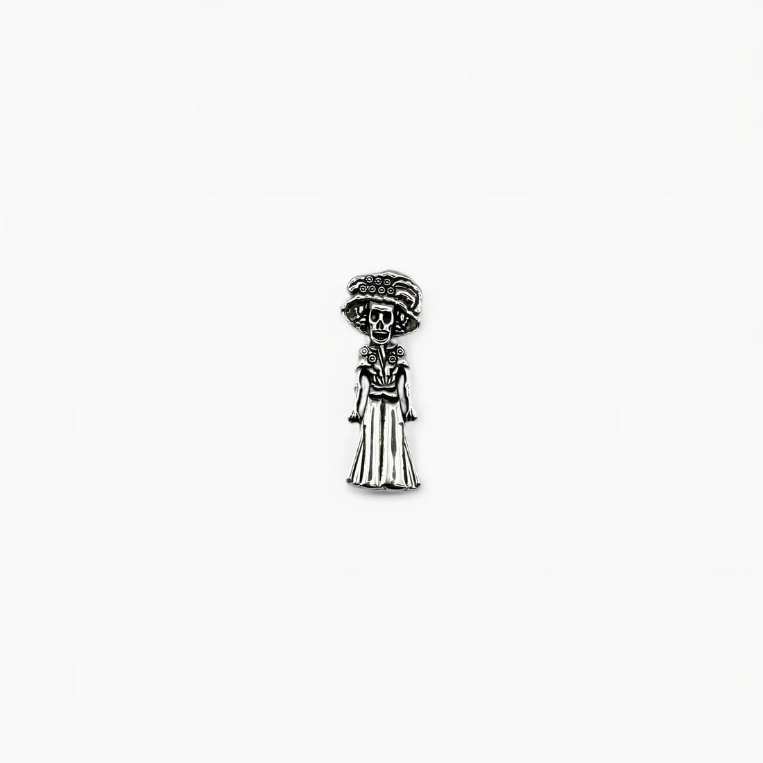 "La Catrina" Mexican Pendant: La Catrina, Mexico’s iconic symbol of Día de los Muertos, is reimagined in this finely crafted silver pendant. With her elegant wide-brimmed hat and flowing dress, this skeletal figure carries both