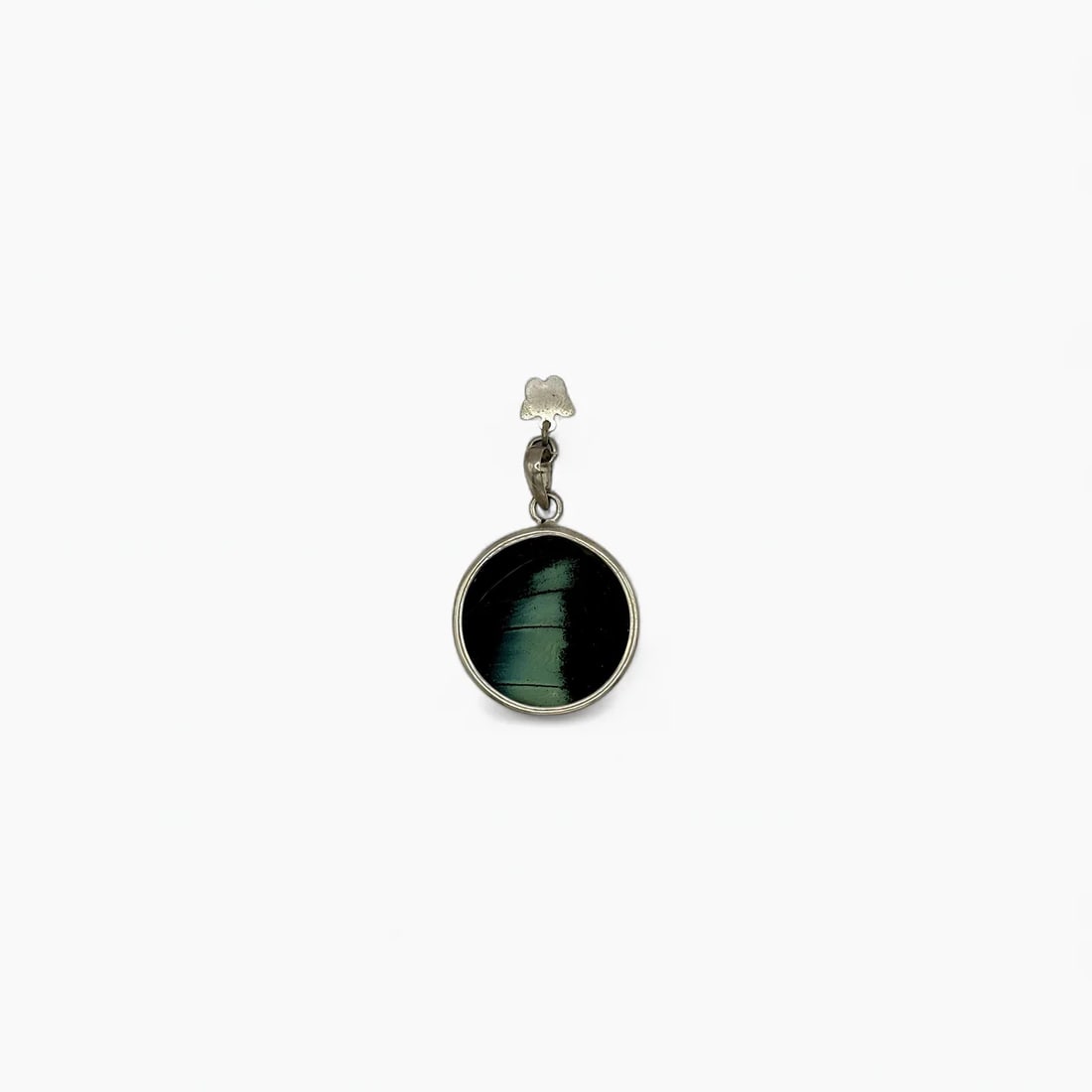 "Whispering Forest" Small Round Butterfly Wing Jewelry Pendant: Handcrafted by Yolanda Ormachea, this double-sided pendant features ethically sourced butterfly wings set in sterling silver. One side glows with iridescent green and black, reminiscent of dense tropi