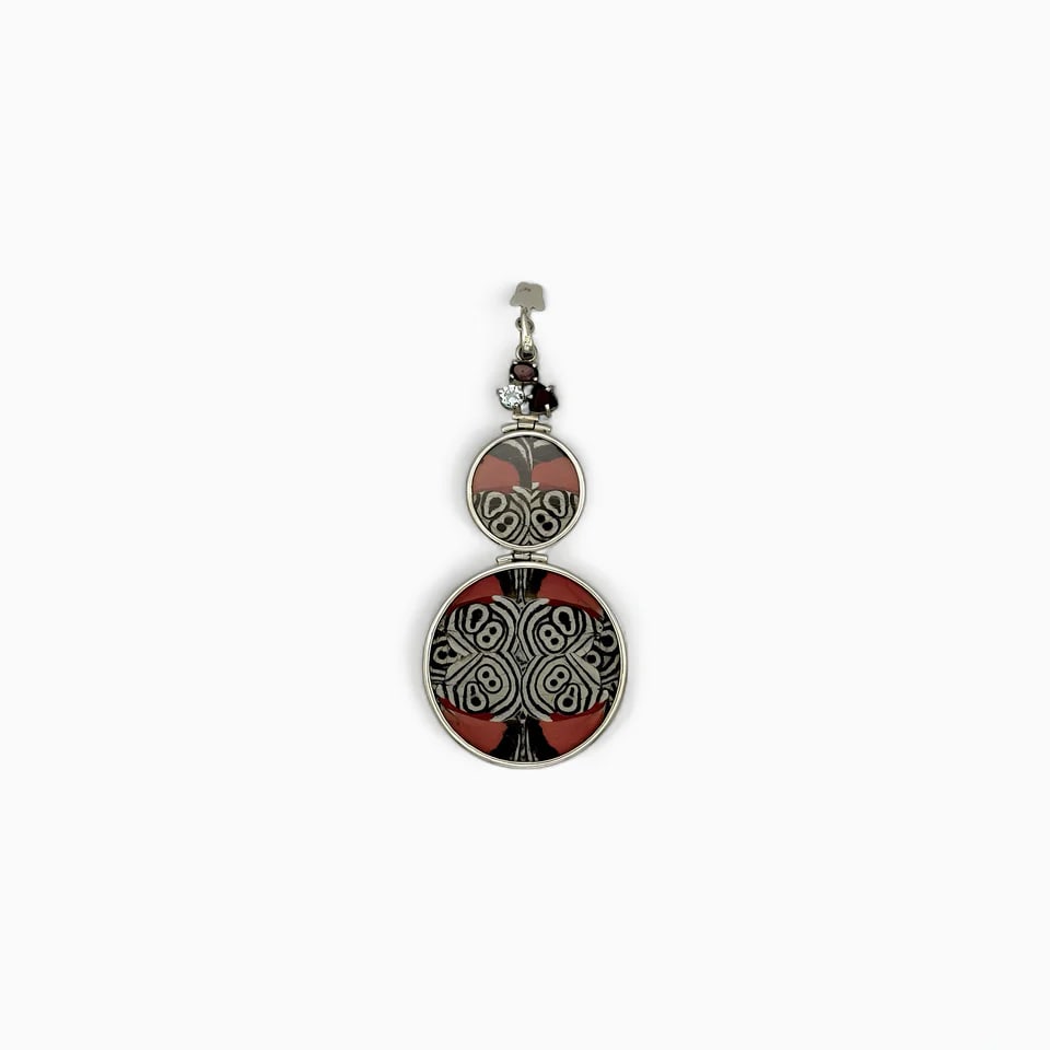"Two Worlds" Double Circle Butterfly Wing Jewelry Pendant: This bold, double-sided pendant by Yolanda Ormachea merges symmetry with storytelling. On one side, vivid red butterfly wings are patterned with intricate black and ivory swirls resembling ancient gly
