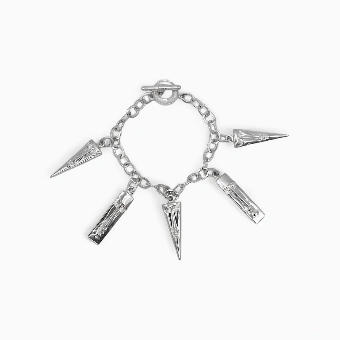 "Compostela Relic: The Talisman" Silver Charm Bracelet: Evoking sacred relics and ancient symbols, the Compostela Relic bracelet by Sergio Bustamante is a modern interpretation of spiritual adornment. Five sculpted sterling silver charms—each engraved wi