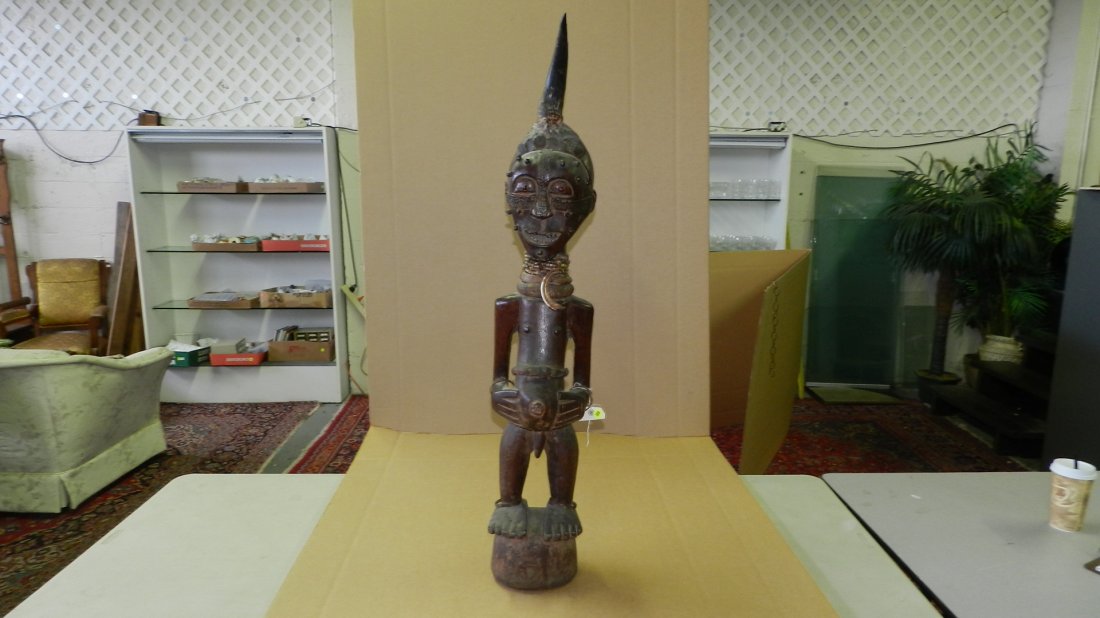 536) African carved Power figure w/ large horn; pegs on: 536) African carved Power figure w/ large horn; pegs on face; inset teeth; snake skin waist band and necklace containing magical substances. From DR Congo, 46"