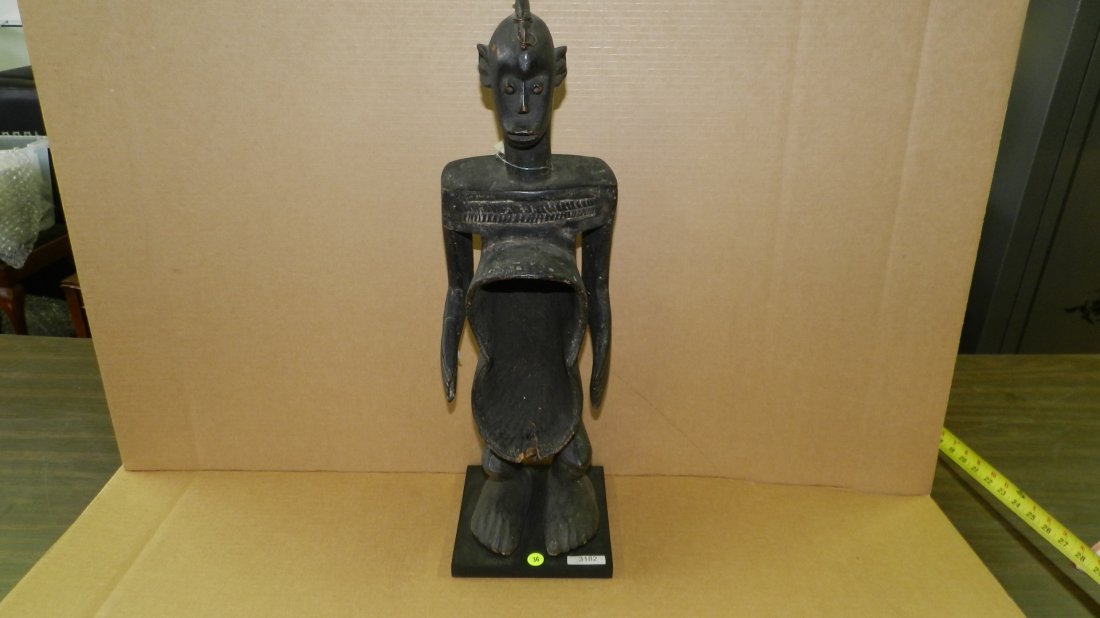 3182) African carved Figural cup, standing asexual: 3182) African carved Figural cup, standing asexual figure. On Stand. 25 1/2" w/stand.