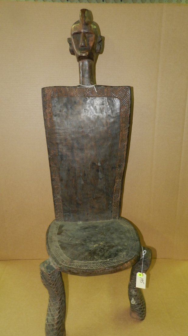 195) East African carved high back chair. Three legs: 195) East African carved high back chair. Three legs supporting round feet. High rectangular back surmounted by abstract human head. Incised geometric ornamentation around edges. COND G, appropriate f