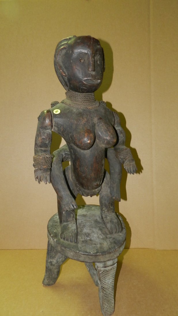 217) great EAST AFRICAN MATERNITY. Brown stained wood: 217) great EAST AFRICAN MATERNITY. Brown stained wood with rope around wrists and neck. Separately carved and attached arms. The female stands on a three legged circular stool with a large infant on h