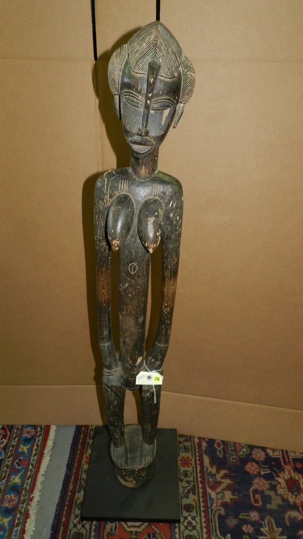140) African SENUFO STANDING FEMALE FIGURE, rhythm: 140) African SENUFO STANDING FEMALE FIGURE, rhythm pounder style. Blackened hardwood. Height 46 inches. Fair condition, insect erosion all over right arm, right arm repaired. Mounted to a base. From I