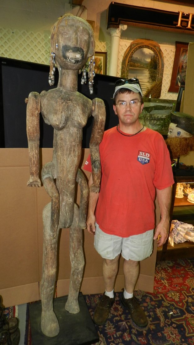 24.1) LARGE EAST AFRICAN FEMALE FIGURE WITH INFANT ON: 24.1) LARGE EAST AFRICAN FEMALE FIGURE WITH INFANT ON HER BACK. Carved wood with weathered brown stain, metal sheet tacked onto right of infant and chin of female and shoulders. Separately carved and 