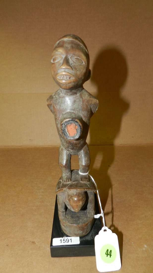 1591) African carved male figure with stomach fetish: 1591) African carved male figure with stomach fetish compartment, standing on turtle. From Dr Congo. 9 1/2" w/stand