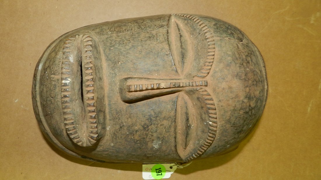 12007) Central African mask, blackened wood with reddis: 12007) Central African mask, blackened wood with reddish brown natural pigments. Hairline cracks and lifted area on forehead, one cog of notching on nose bridge chipped. 10"