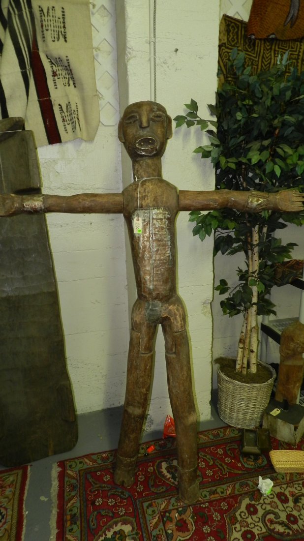 820) EAST AFRICAN STANDING FIGURE WITH ARMS OUTSTRETCHE: 820) EAST AFRICAN STANDING FIGURE WITH ARMS OUTSTRETCHED. Carved wood with weathered brown stain. Separately carved and attached limbs. Metal sheets tacked onto shoulders, abdomen, groin, wrists, and 