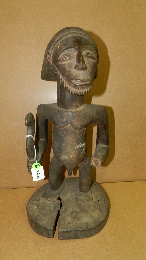 Standing Hemba male figure with missing arm. Holding a: Standing Hemba male figure with missing arm. Holding a sickle knife on integral pedestal. 18 1/2